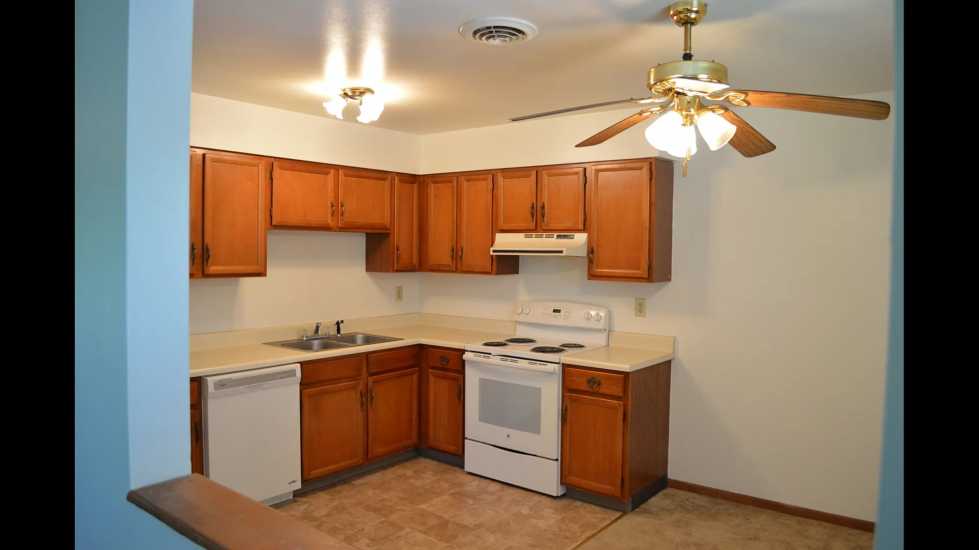 Charming kitchen with rich wooden cabinetry, sleek countertops, and modern appliances under warm lighting.