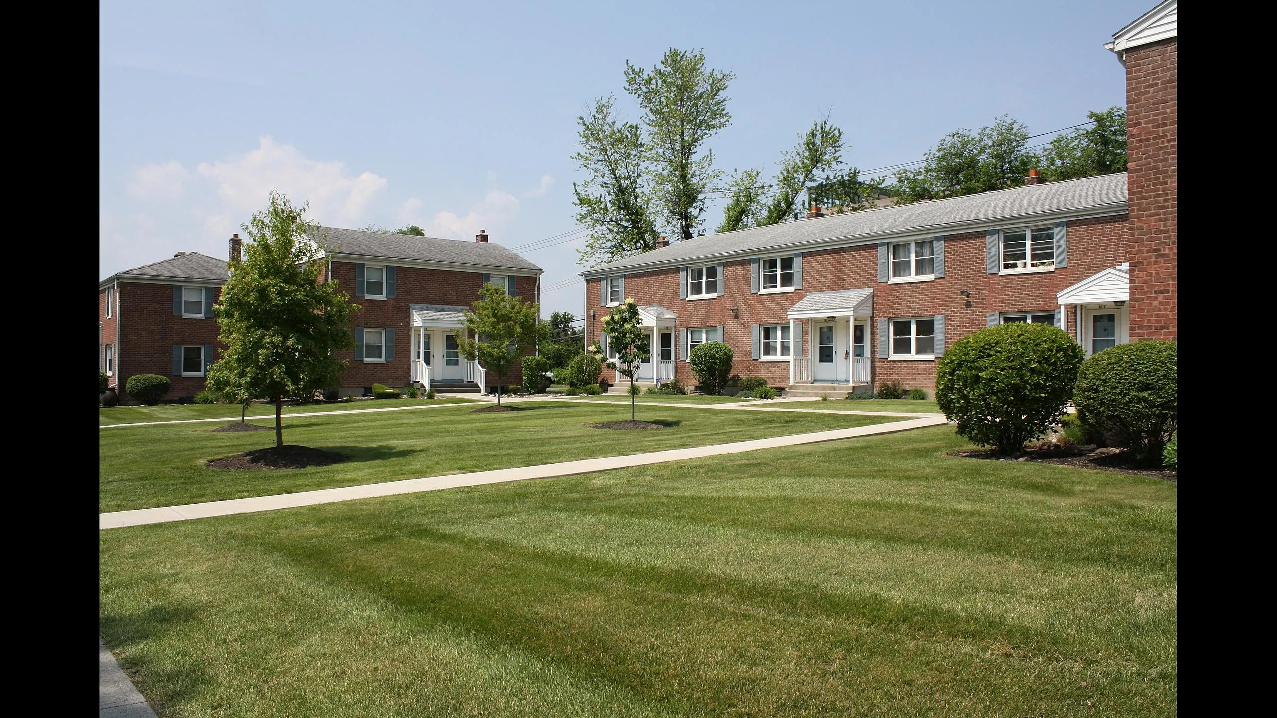 Brick townhouse-style apartment buildings and landscaped courtyard at Adams Park Apartments in Albany, NY