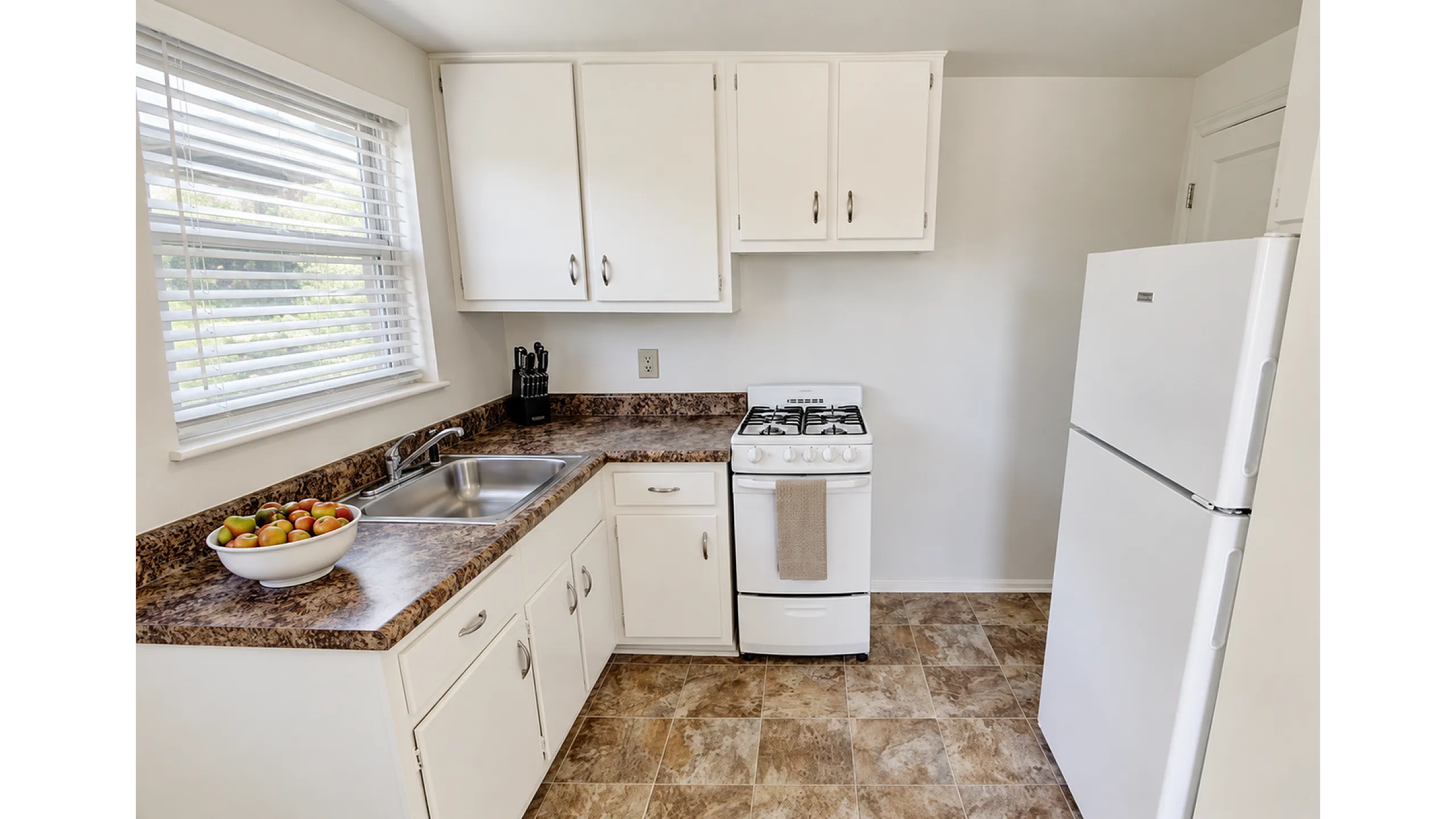 Apartment kitchen with gas range, full-size refrigerator and window at Adams Park Apartments