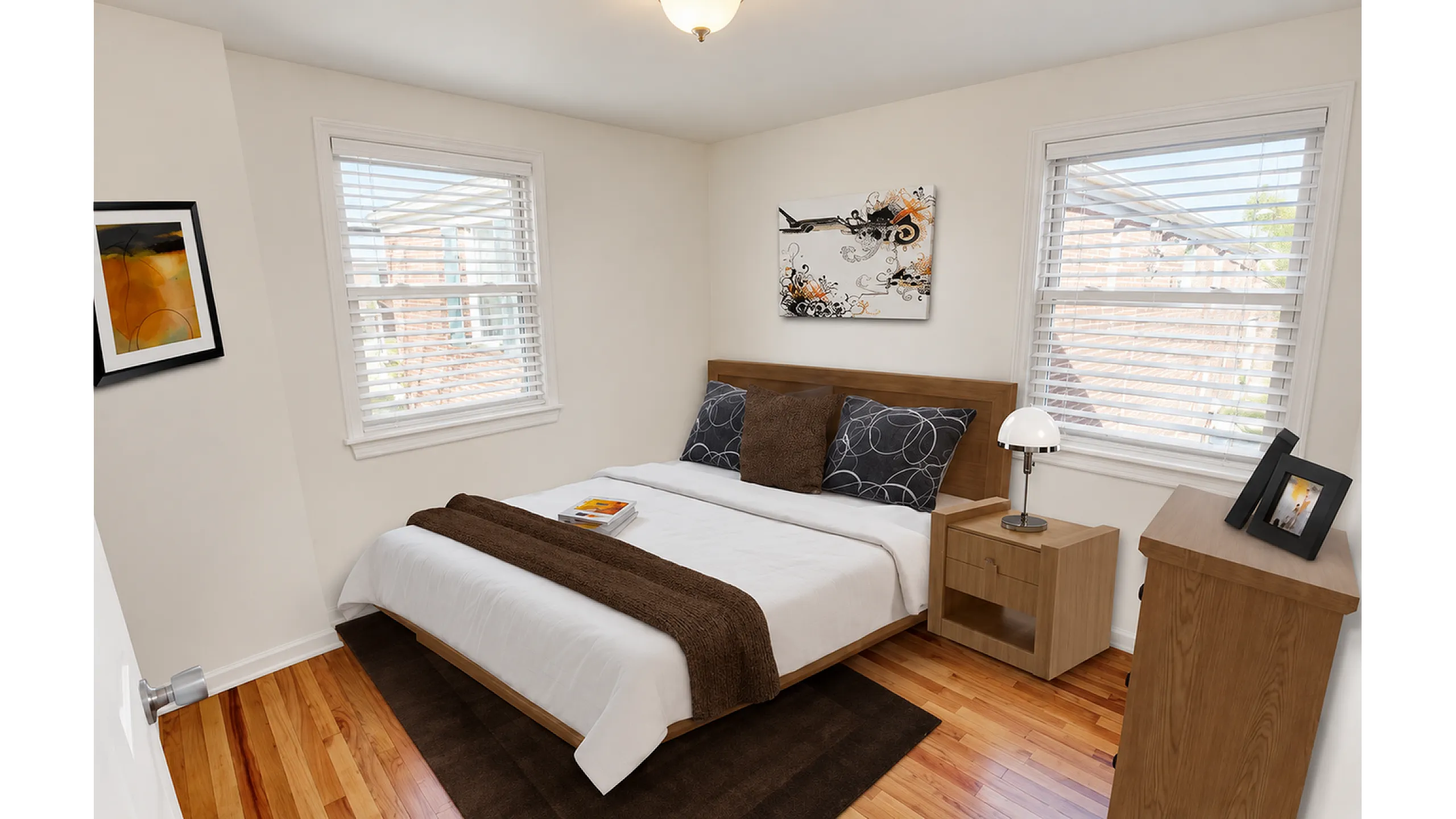 Furnished bedroom with large window and white blinds at Adams Park Apartments
