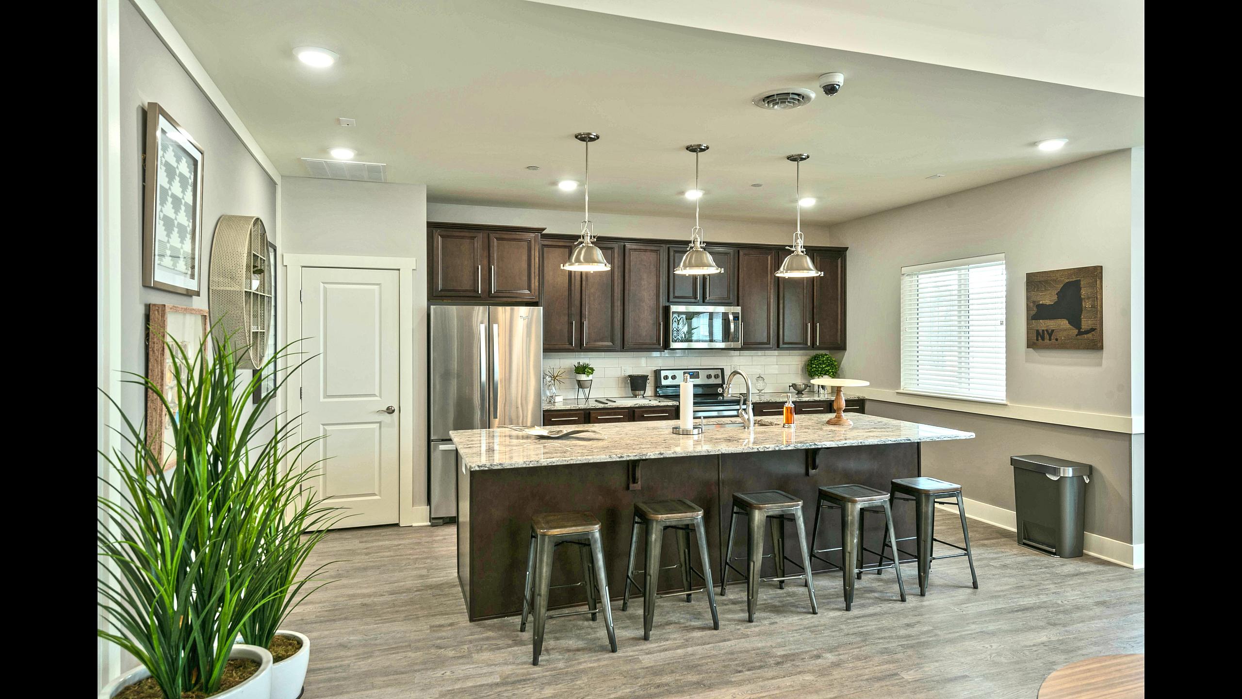 Clubhouse kitchen with granite island, bar seating and stainless steel appliances at Van Allen Apartments