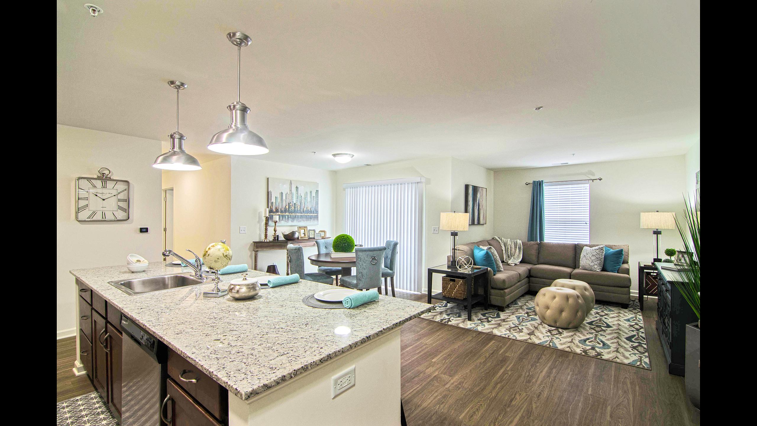 Open-concept living room and kitchen with granite island at Van Allen Apartments