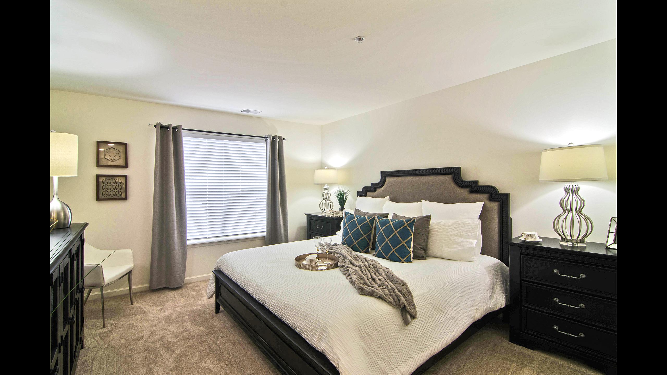 Furnished master bedroom with large window and carpeting at Van Allen Apartments