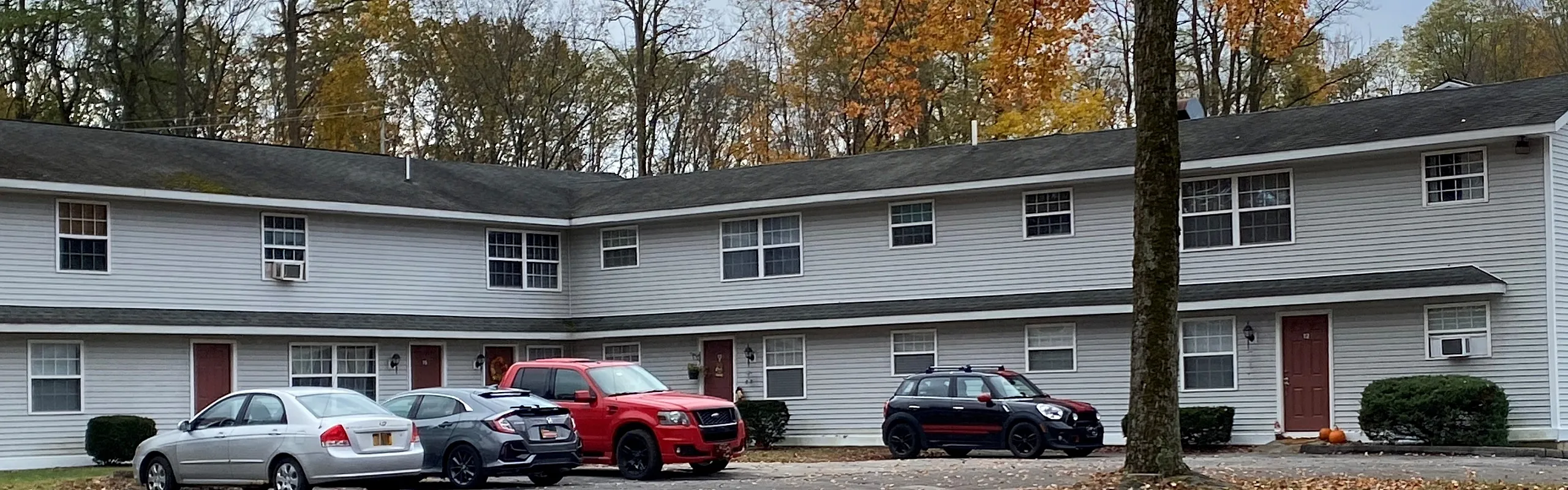 Two-story apartment building with autumn foliage at Canfield Apartments in Gansevoort, NY