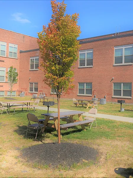Landscaped courtyard with picnic tables outside the historic brick schoolhouse at Draper Lofts in Rotterdam, NY