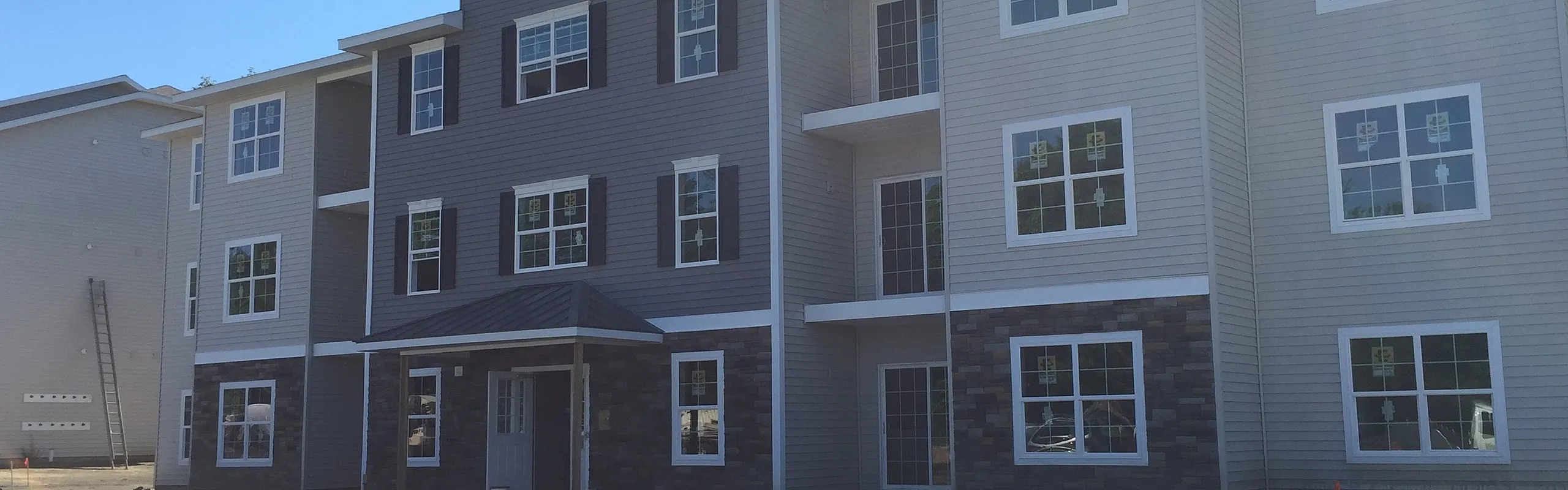 Three-story apartment building with stone accents and private balconies at Van Allen Apartments in North Greenbush, NY