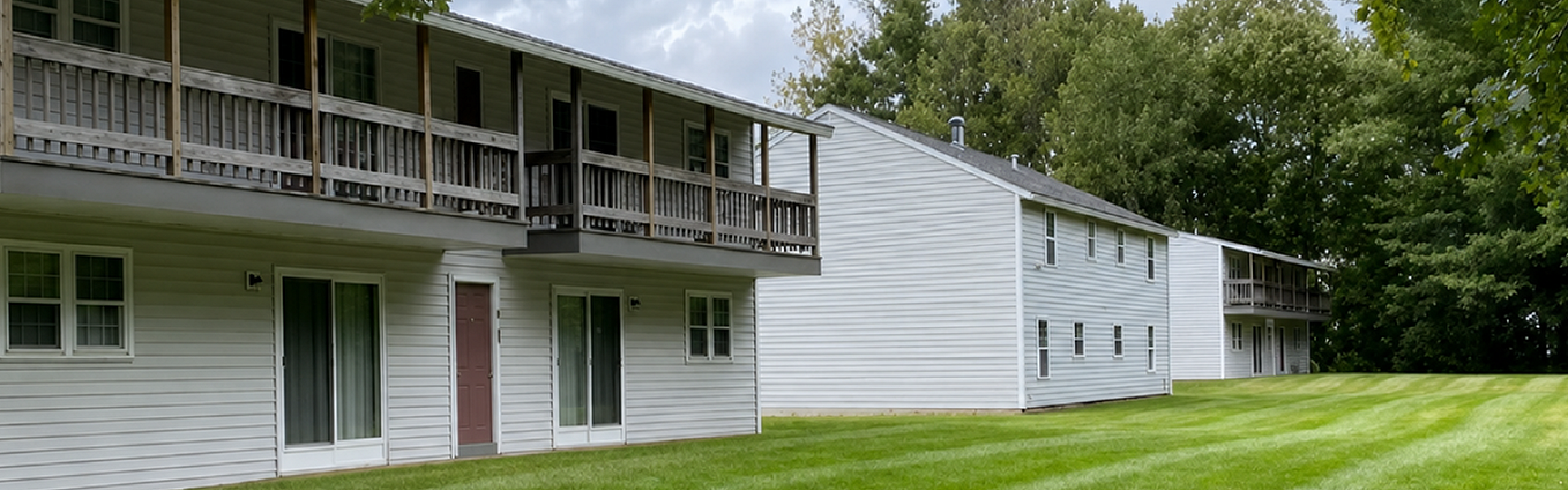 Apartment buildings with private balconies overlooking open lawn at Halfmoon Garden Apartments in Clifton Park, NY