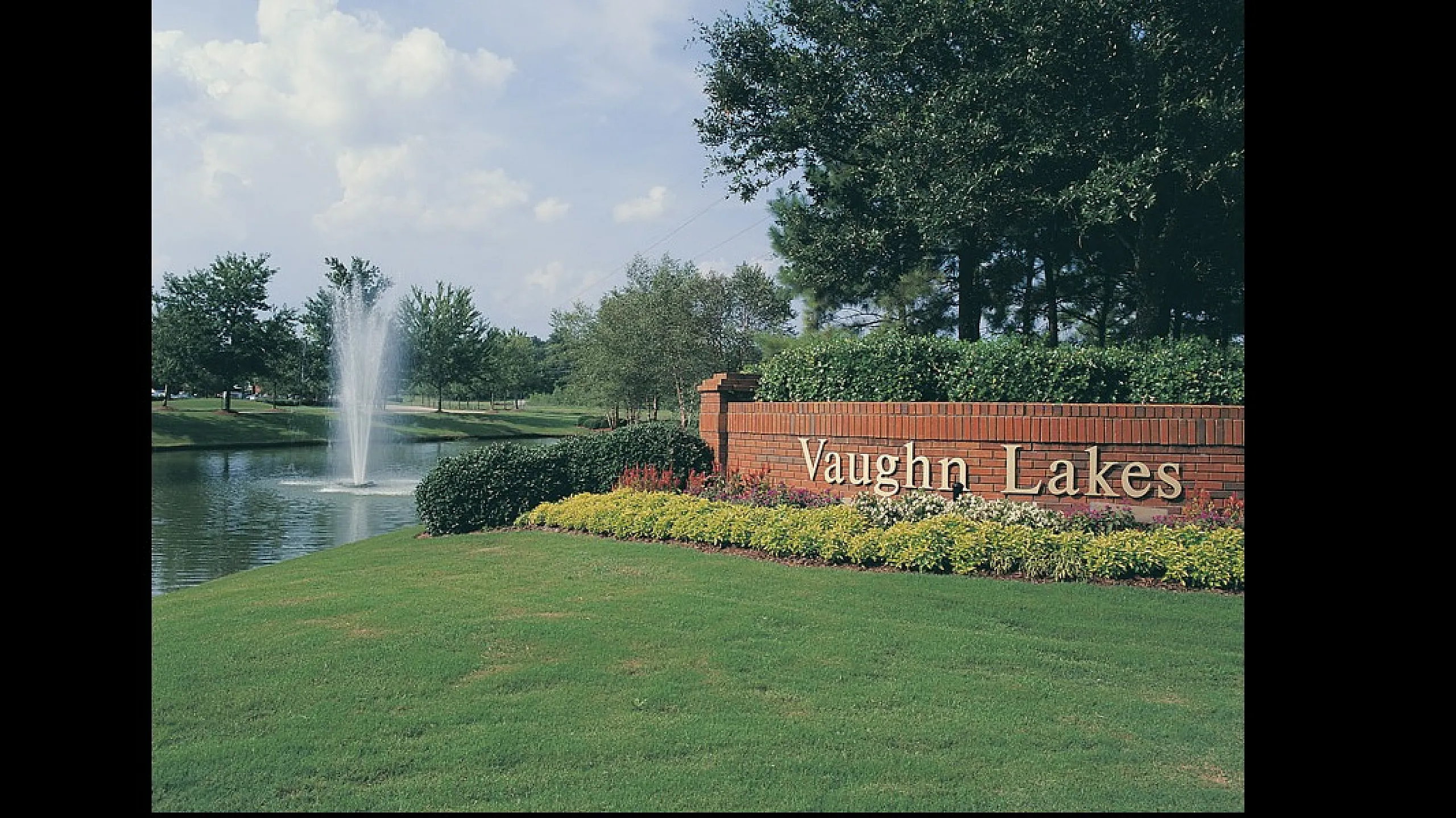 Charming entrance to Vaughn Lakes with lush greenery and a serene pond featuring a beautiful fountain.