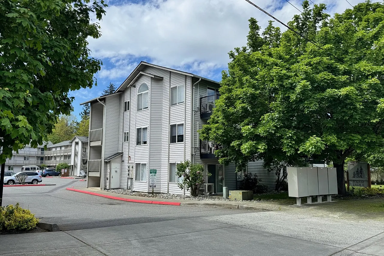 Charming apartment complex surrounded by lush greenery, featuring modern architecture and ample parking.