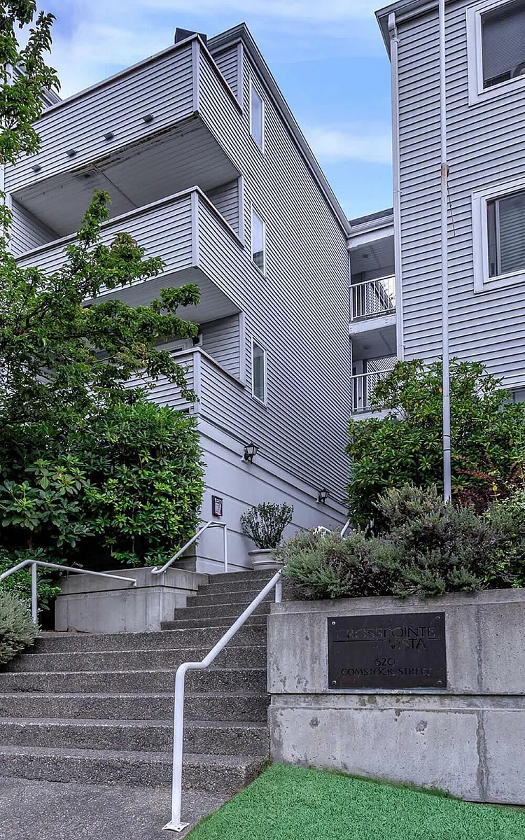Inviting modern apartment complex with lush greenery, featuring stylish balconies and a welcoming stairway entrance.