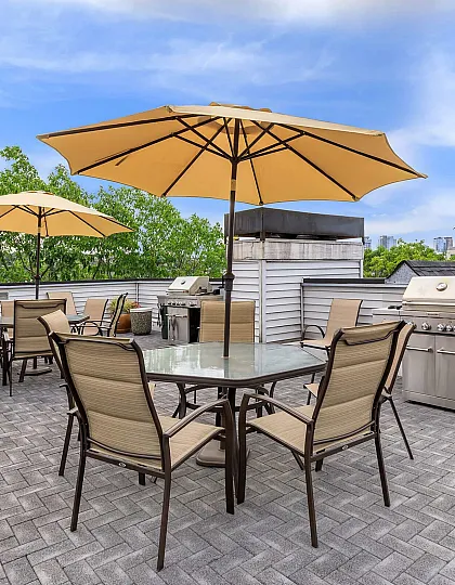 Spacious rooftop terrace with elegant seating and umbrellas, offering stunning city views and a built-in grill for perfect outdoor entertaining.
