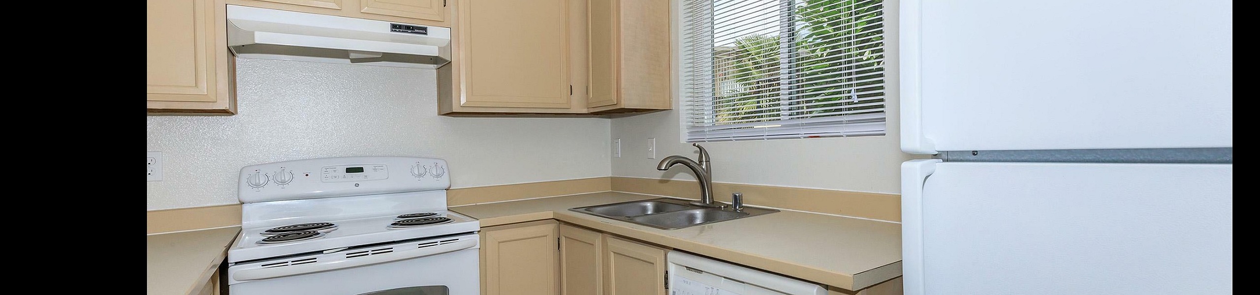 Charming kitchen with natural light, featuring modern appliances, creamy cabinetry, and a bright atmosphere.