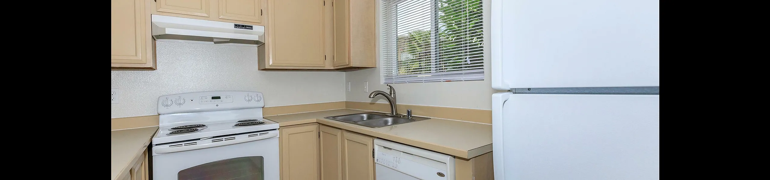 Bright, modern kitchen with sleek white appliances, ample cabinetry, and a large window inviting natural light.