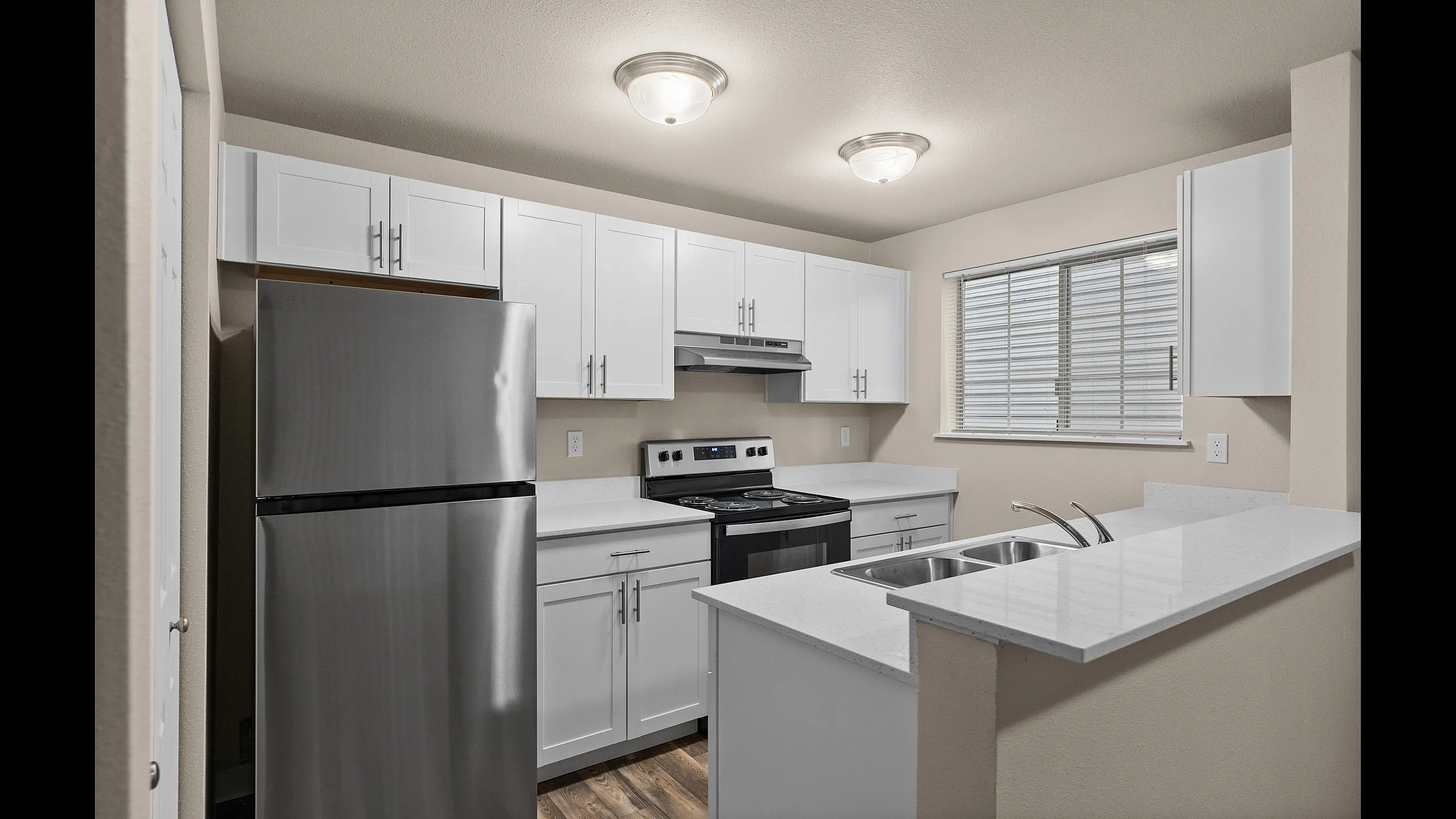 Modern kitchen with sleek stainless steel appliances, elegant white cabinetry, and ample natural light.