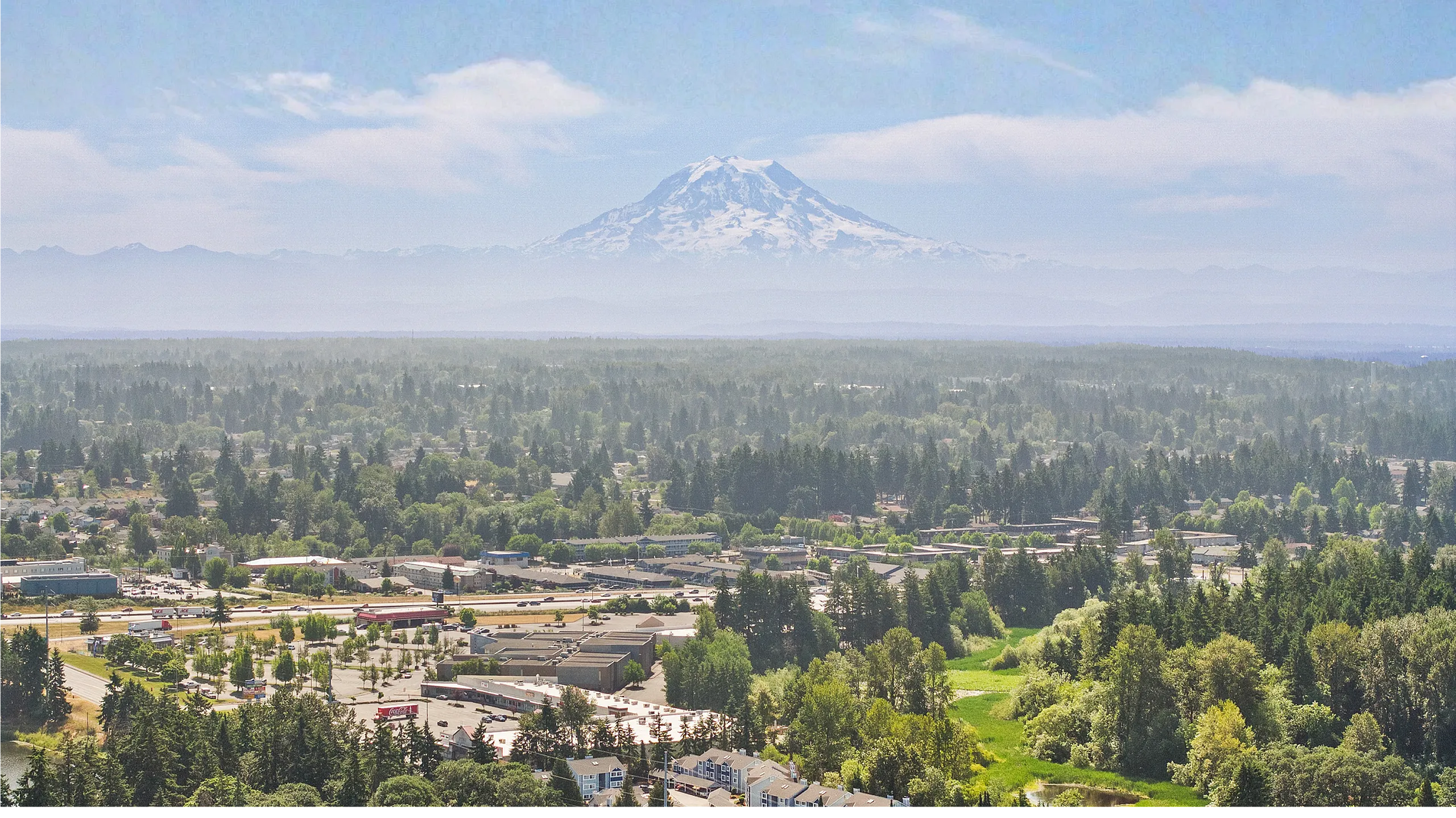 Breathtaking aerial view of a lush, green community with a stunning mountain backdrop, ideal for tranquil living.