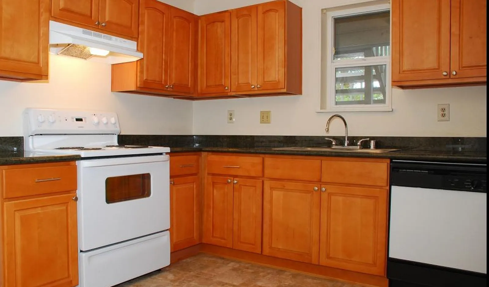 Inviting kitchen with warm wooden cabinetry, modern appliances, and ample natural light, perfect for culinary adventures.