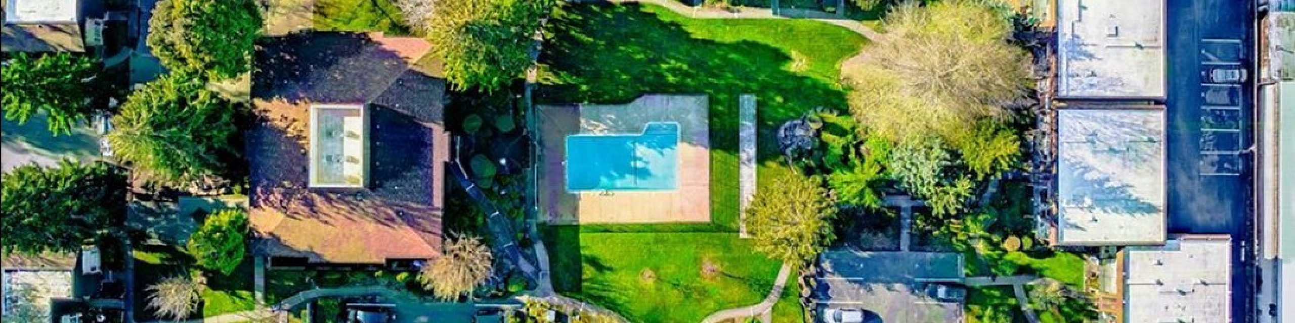 Vibrant aerial view of modern apartment complex featuring lush landscaping, a sparkling swimming pool, and ample parking space, perfect for luxurious living.