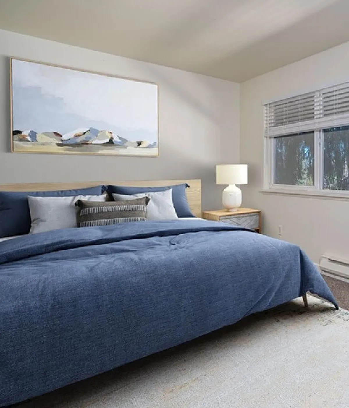Elegant bedroom showcasing a cozy blue bedding set, modern nightstand with a sleek lamp, large window with blinds, and a stylish wooden dresser adorned with decorative vases and a contemporary wall art piece.