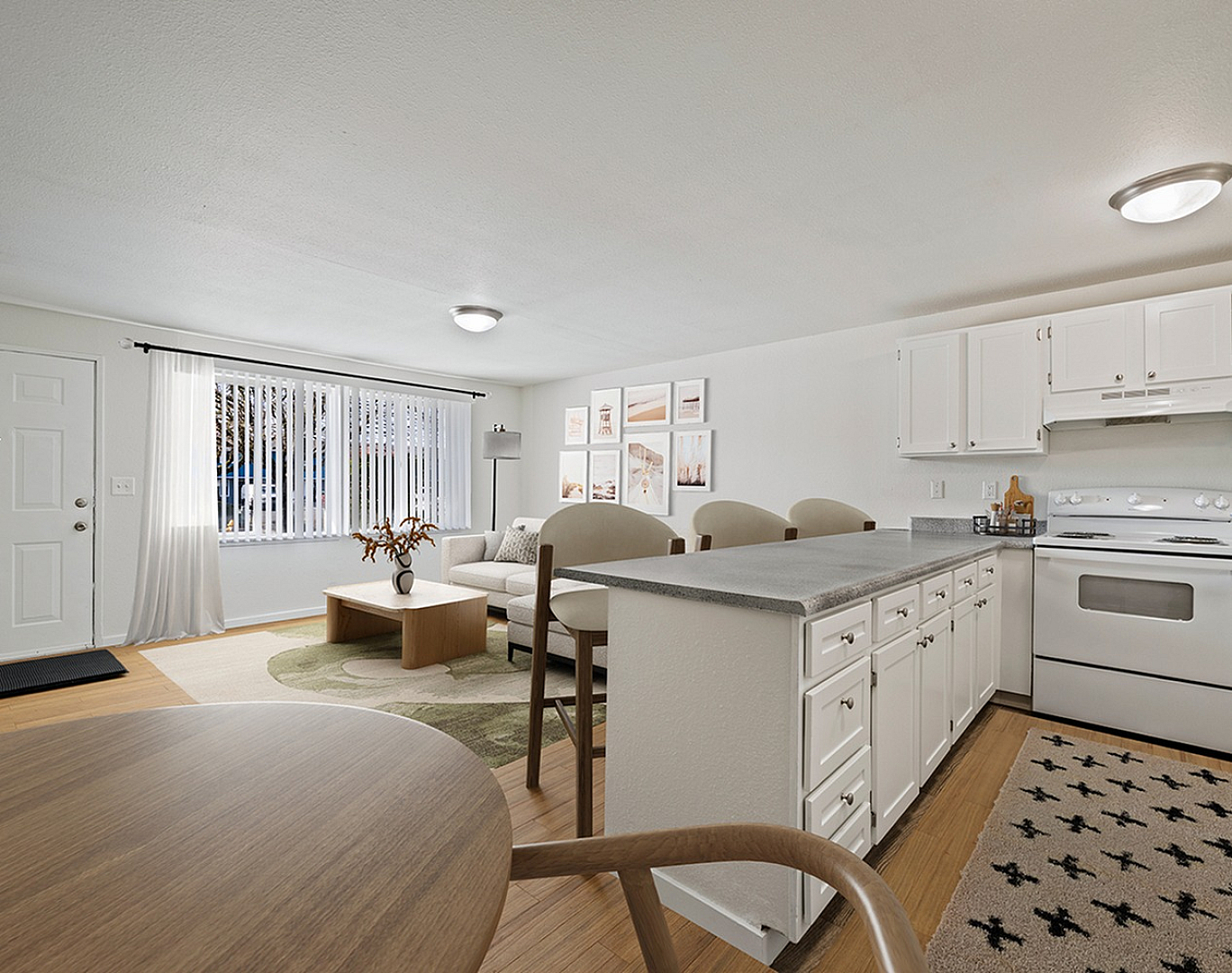 Bright, open-concept living and kitchen area with modern white cabinets, elegant decor, and cozy seating, offering a welcoming atmosphere.