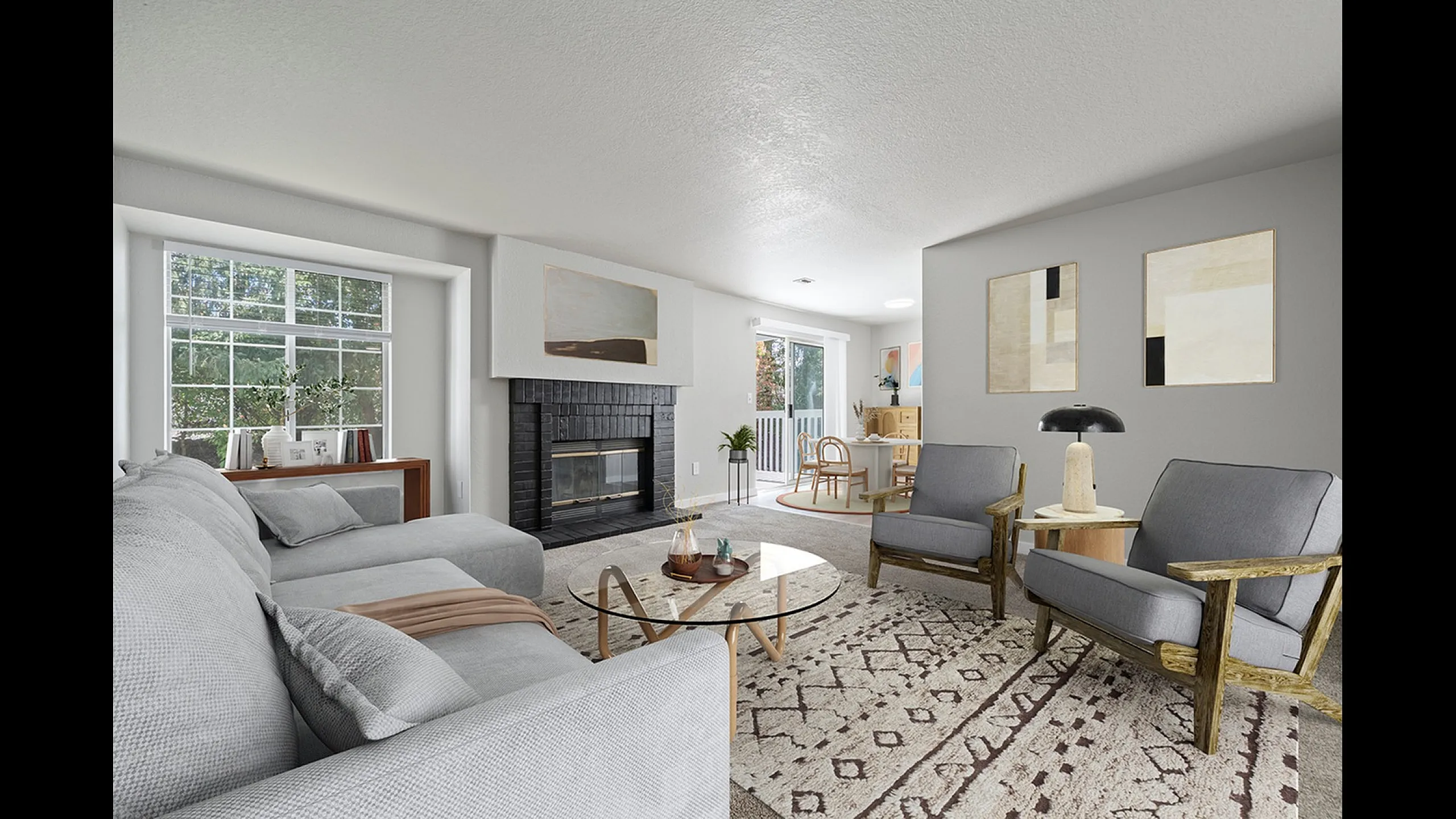 Inviting living room with elegant gray sofa, chic glass coffee table, and cozy fireplace, adjoining a bright dining area with outdoor view.