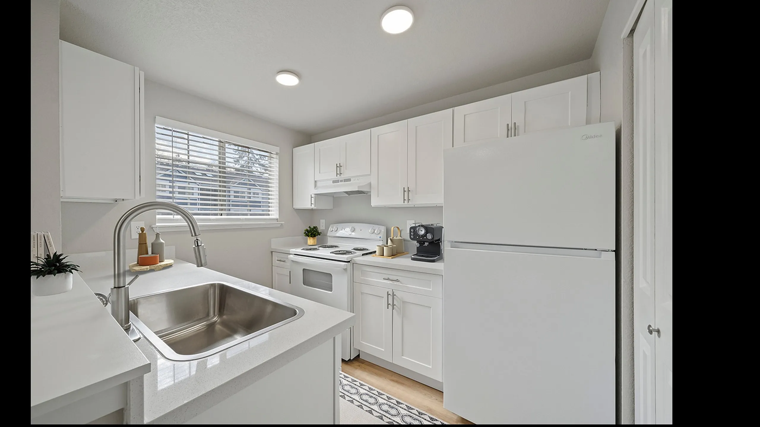 Modern kitchen with sleek white cabinetry, stainless steel sink, and spacious countertops, perfect for culinary creativity.