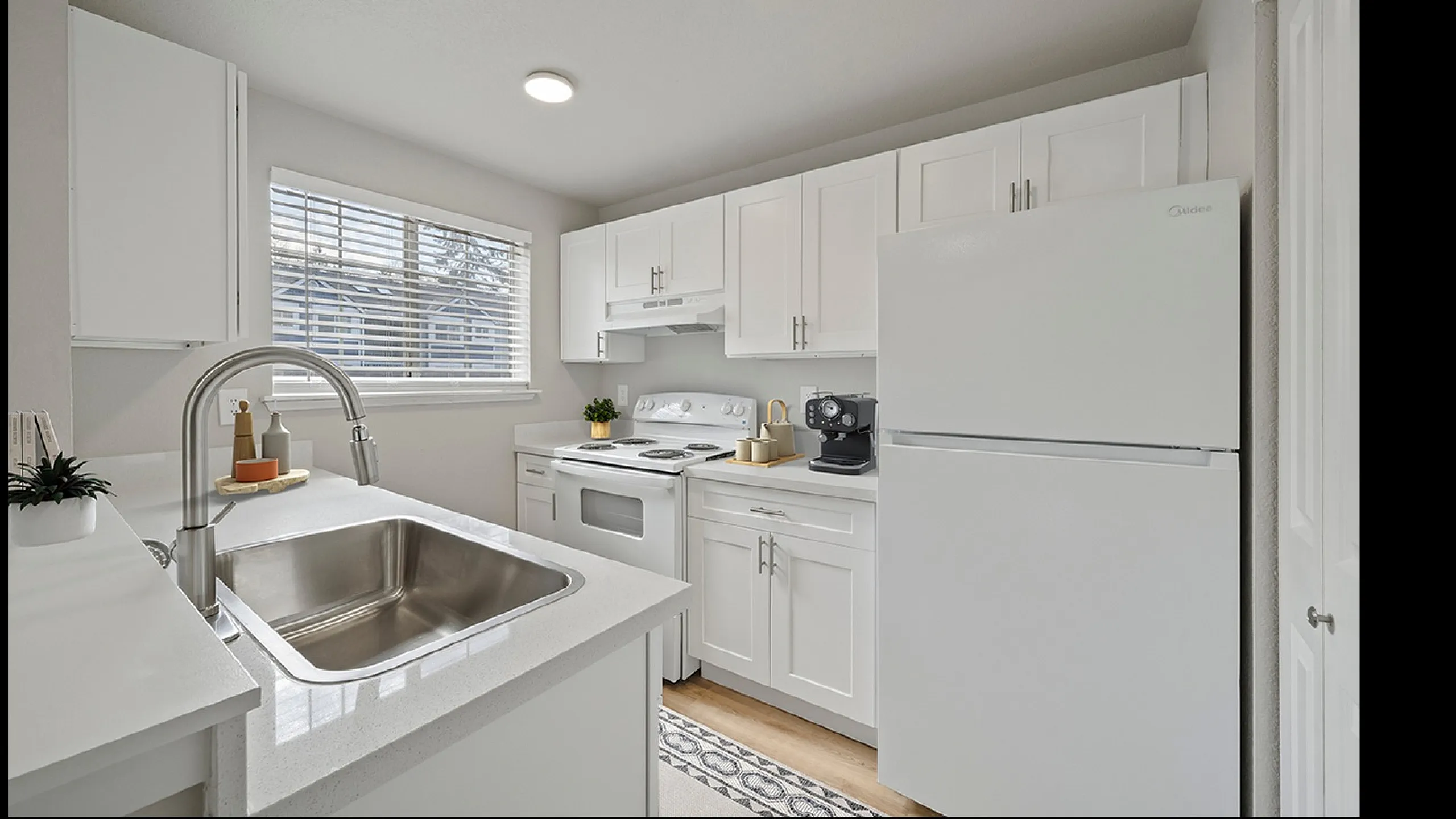 Modern kitchen with sleek white cabinets, spacious countertop, and stainless steel sink, illuminated by natural light.