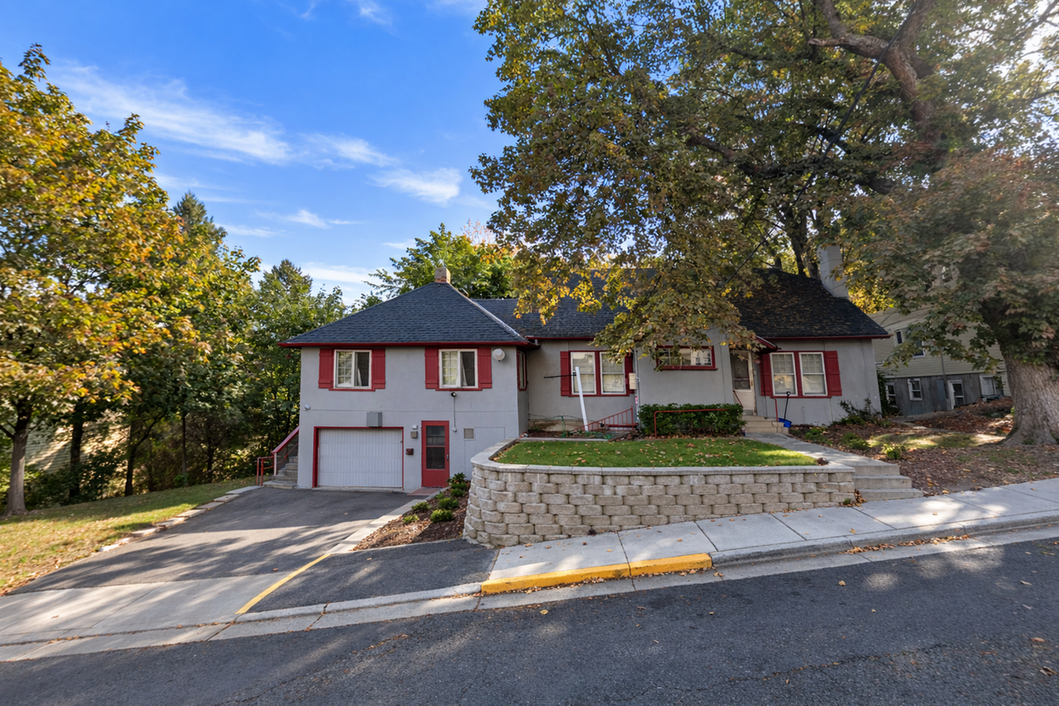 Coug Housing suburban home with red shutters, nestled among mature trees and featuring a spacious front yard.
