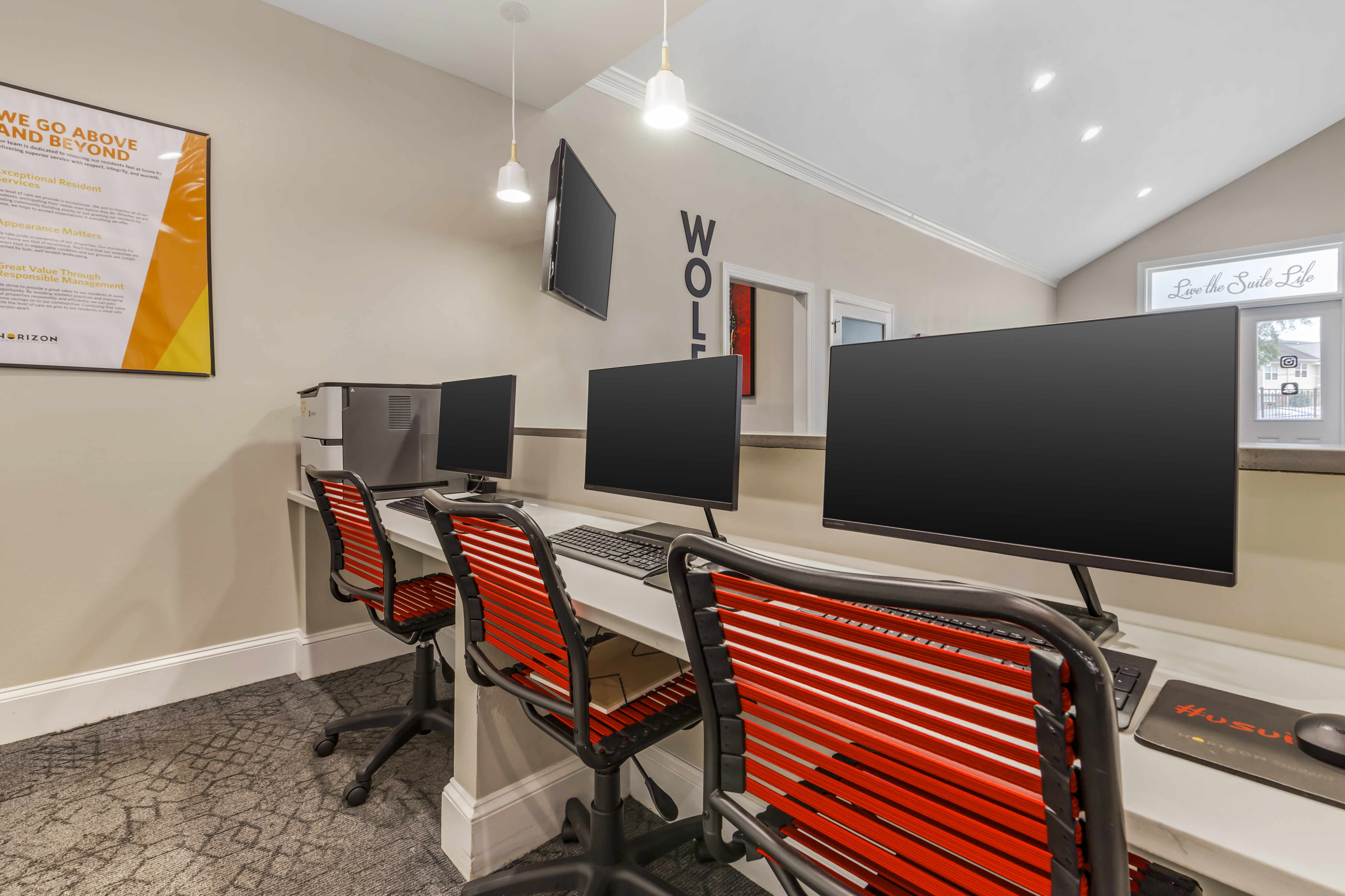 Contemporary office space with three workstations, stylish red chairs, and sleek monitors.