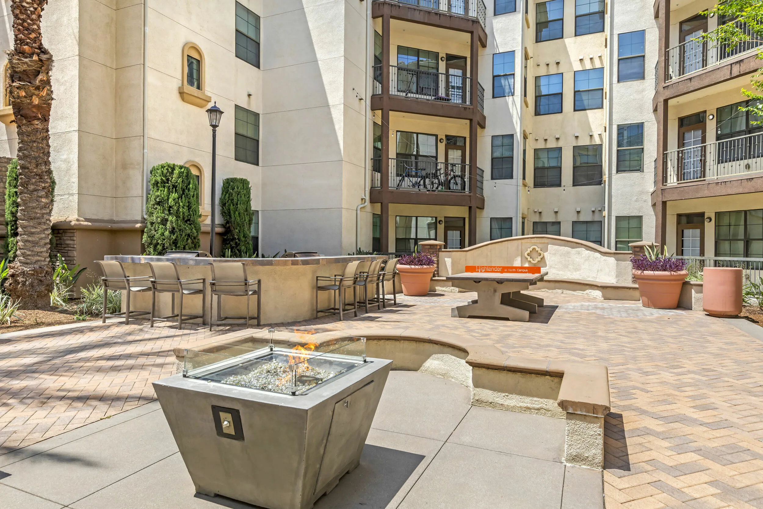 Highlander at North Campus landscaped courtyard with fire pit, elegant seating area, and lush greenery in Riverside CA