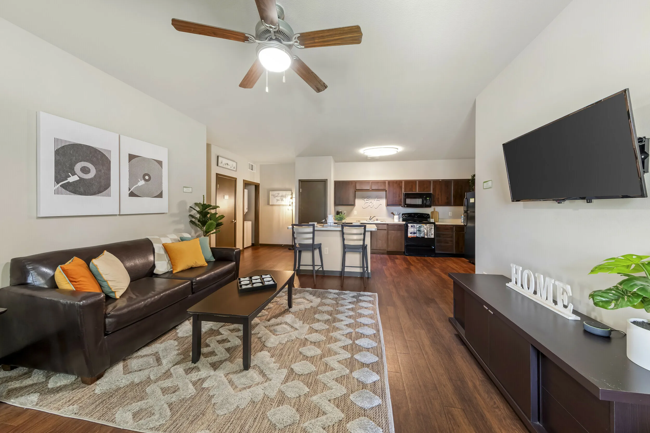 Highlander at North Campus open-concept living room with plush leather sofa and modern kitchen area in Riverside CA