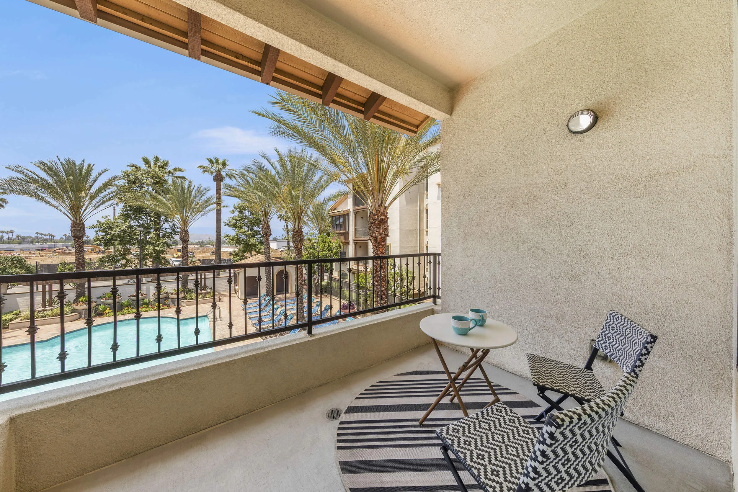 Highlander at North Campus apartment balcony with stylish seating overlooking the pool and palm trees in Riverside CA
