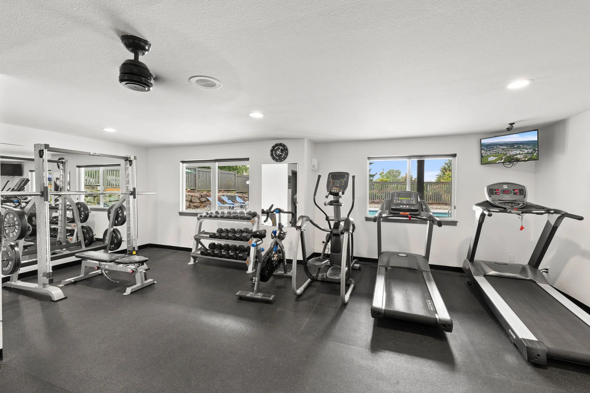 Modern fitness room with professional gym equipment, including treadmills, weights, and cardio machines, offering a bright and inviting workout space.