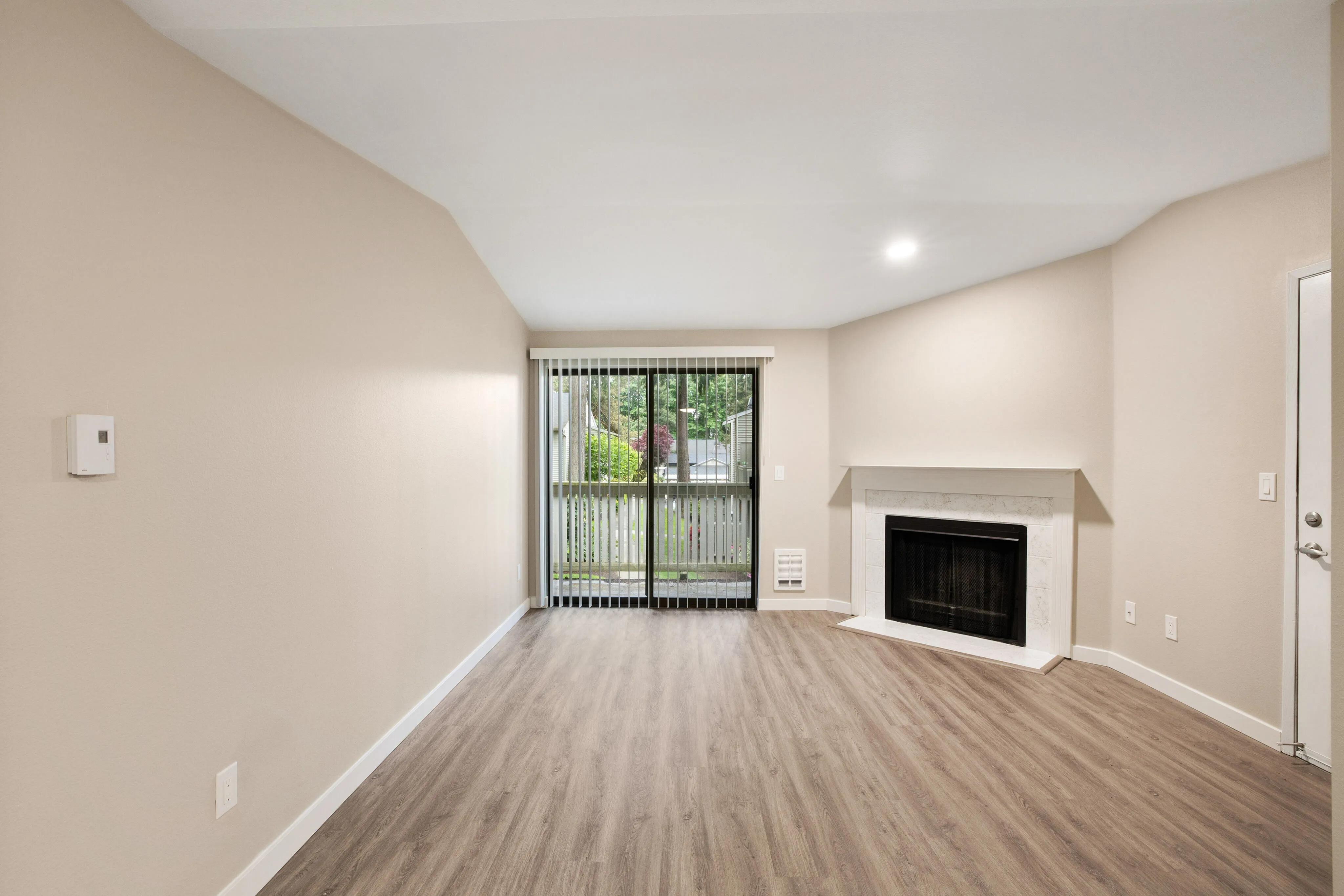 Elegant living room with modern laminate flooring, large sliding glass door to a private patio, and a cozy fireplace.