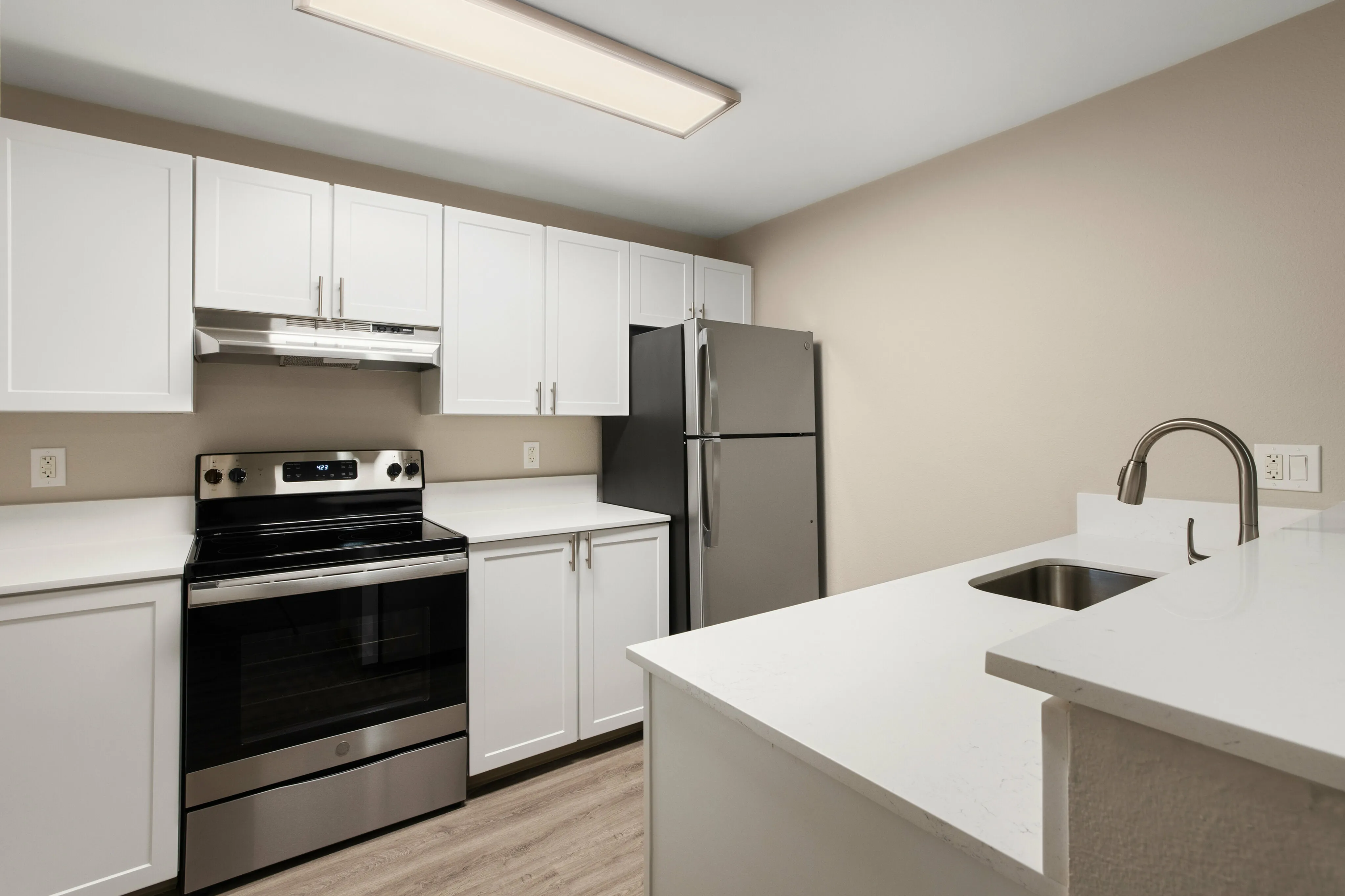 Modern kitchen with sleek stainless steel appliances, pristine white cabinetry, and elegant countertops.