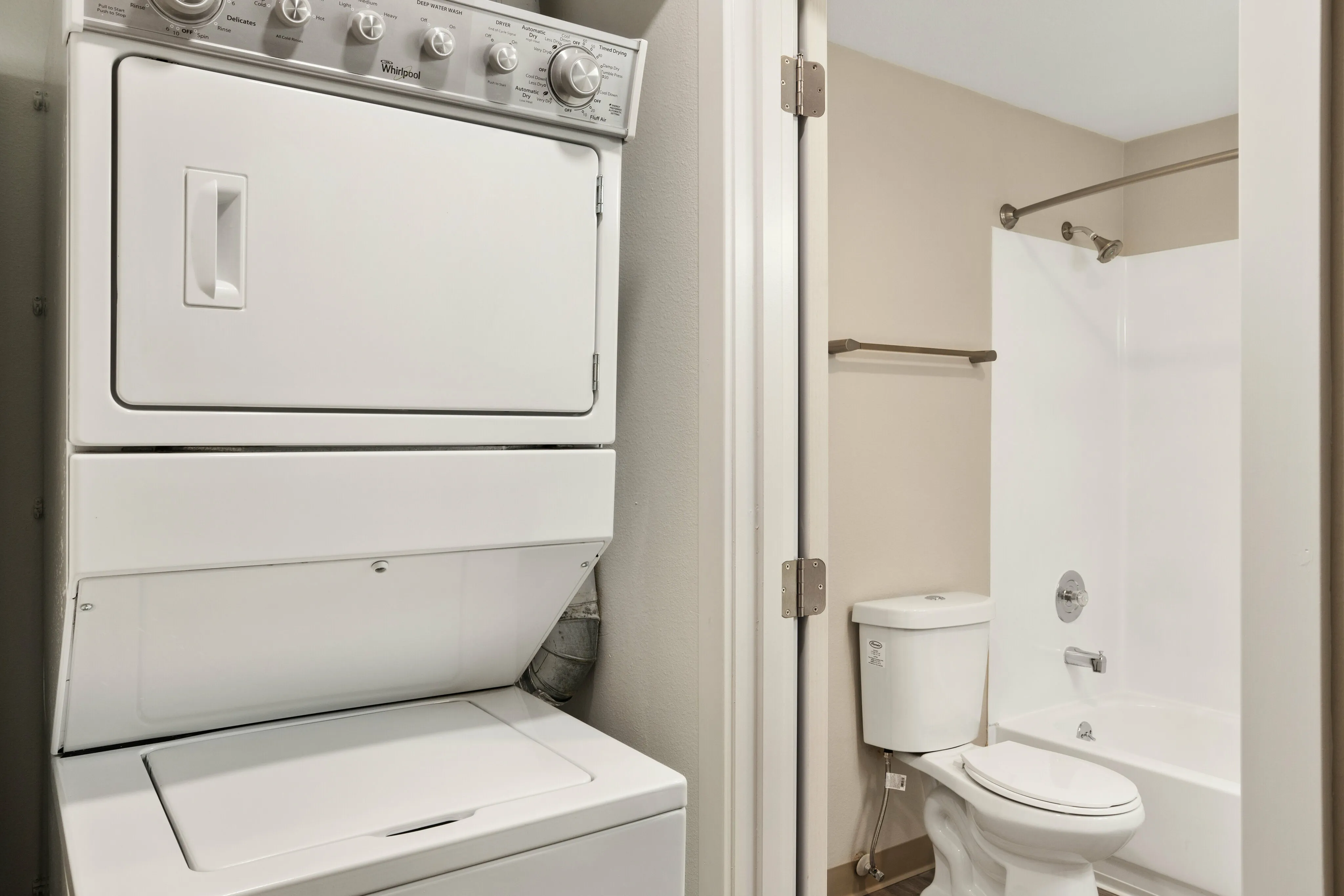 Modern apartment bathroom with sleek washer-dryer combo and pristine bathtub, highlighting convenient in-unit laundry feature.