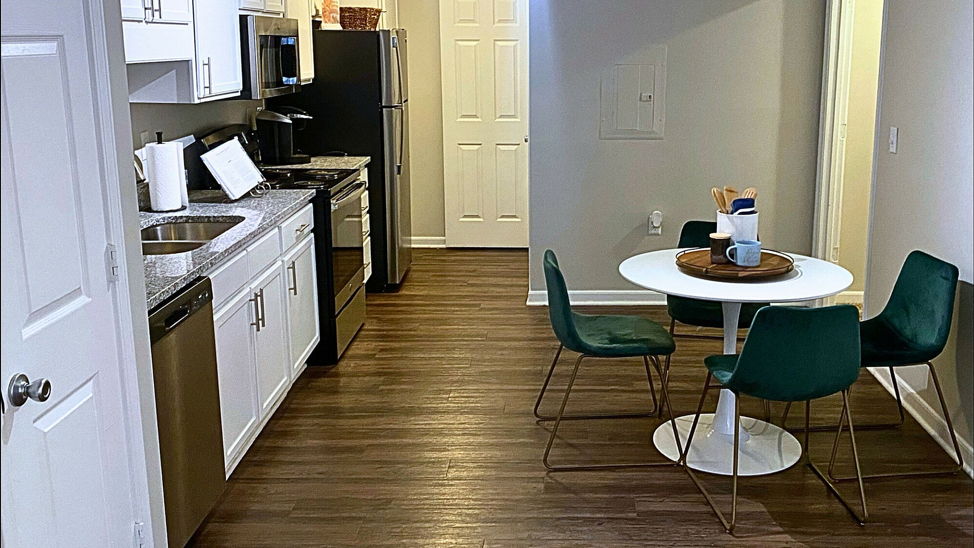 Contemporary kitchen with sleek white cabinets and adjoining dining area with a round table and green chairs.