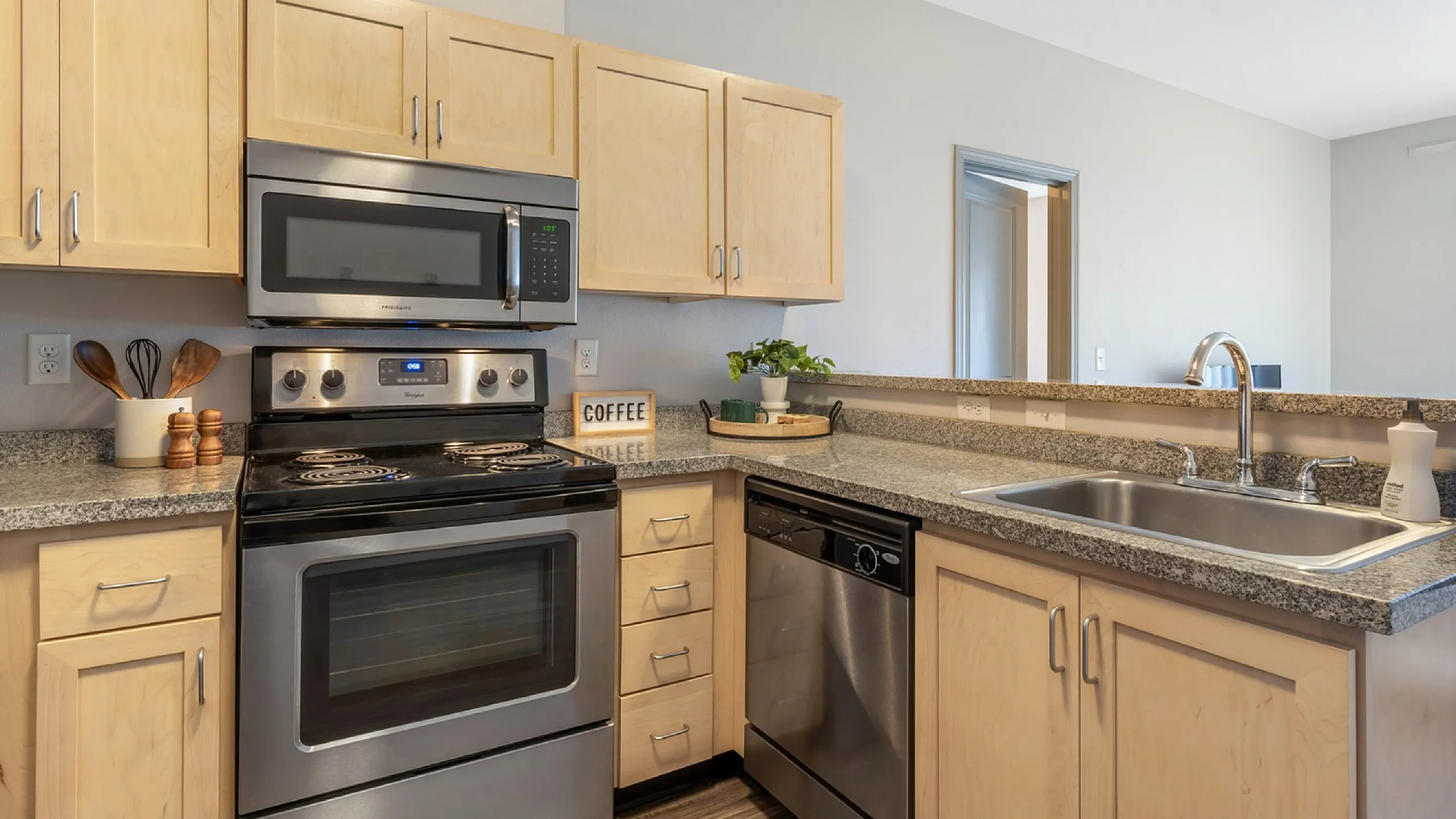 Modern kitchen with light wood cabinets, stainless steel appliances, and granite countertops.