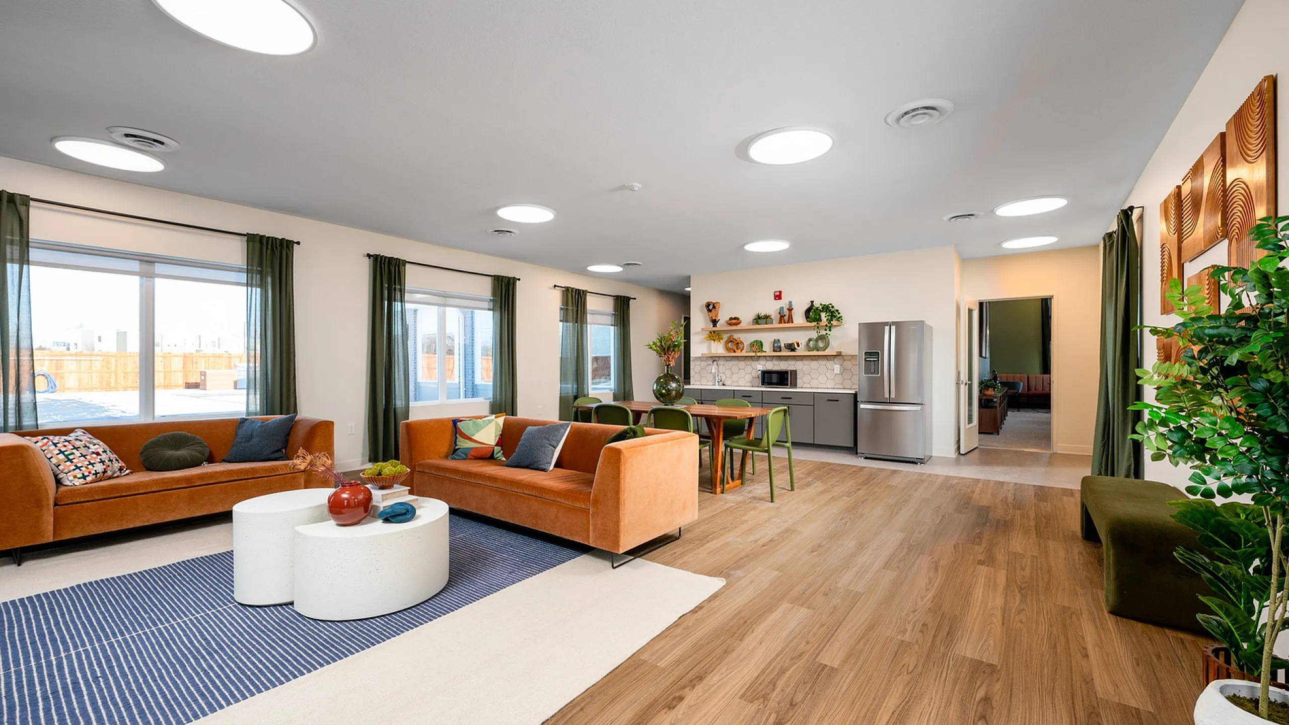 Modern open-plan living area with stylish sofas, vibrant decor, and a sleek kitchen, perfect for entertaining.