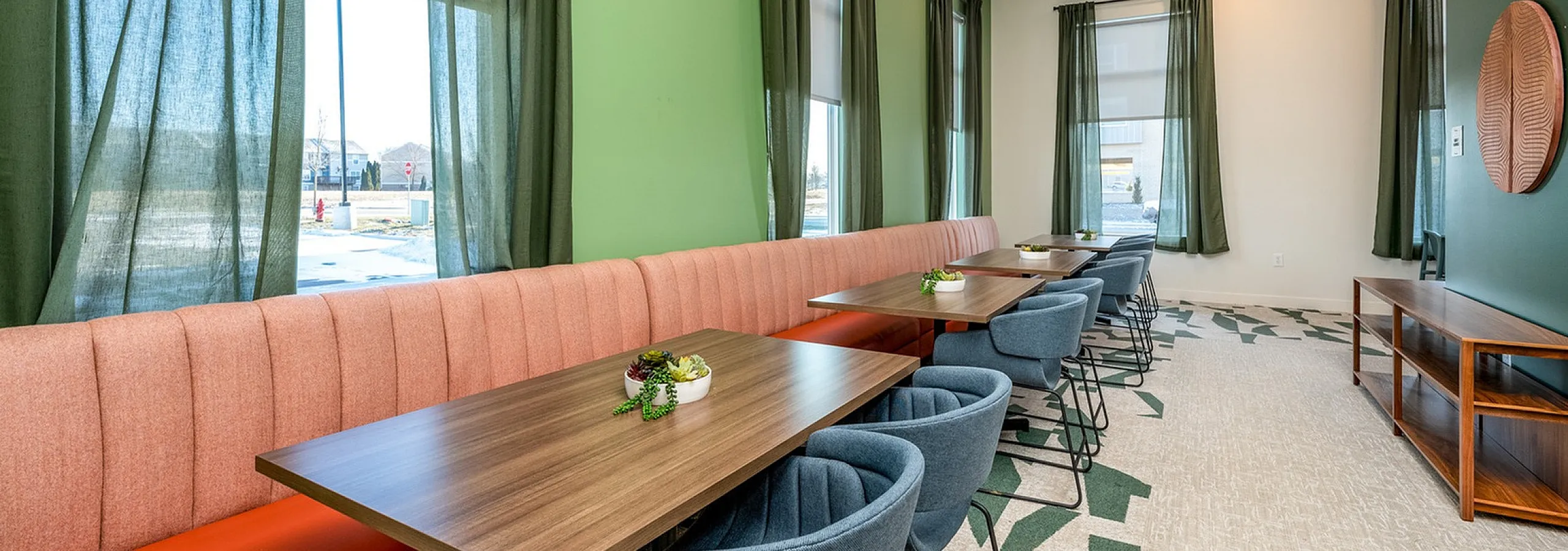 Stylish communal dining area with modern seating and vibrant green walls at Wabash Lofts student apartments near Purdue in West Lafayette Indiana