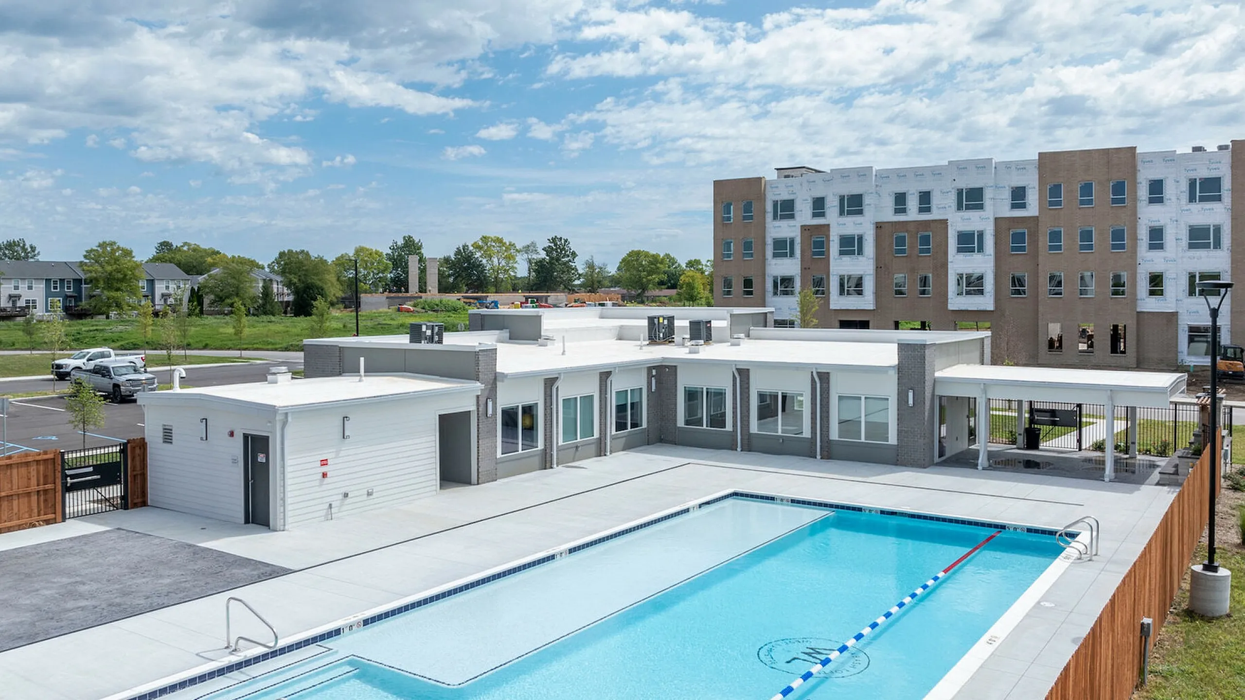 Modern apartment complex showcasing a pristine swimming pool surrounded by a spacious outdoor area, perfect for relaxation and leisure.
