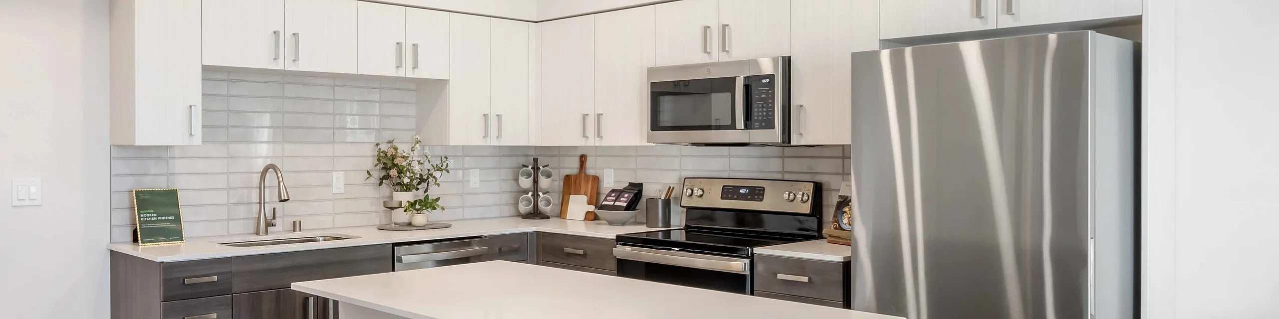 Modern kitchen with sleek stainless steel appliances, white cabinetry, and a stylish island with bar stools, set in a spacious, well-lit area.
