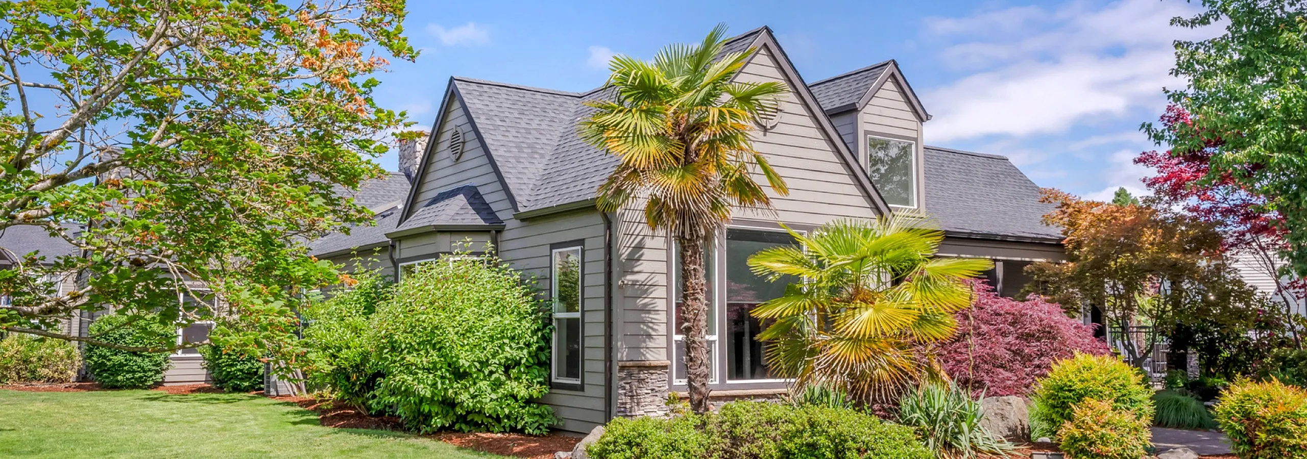 Chase Village cottage-style home surrounded by lush greenery and vibrant landscaping, offering a serene suburban retreat.