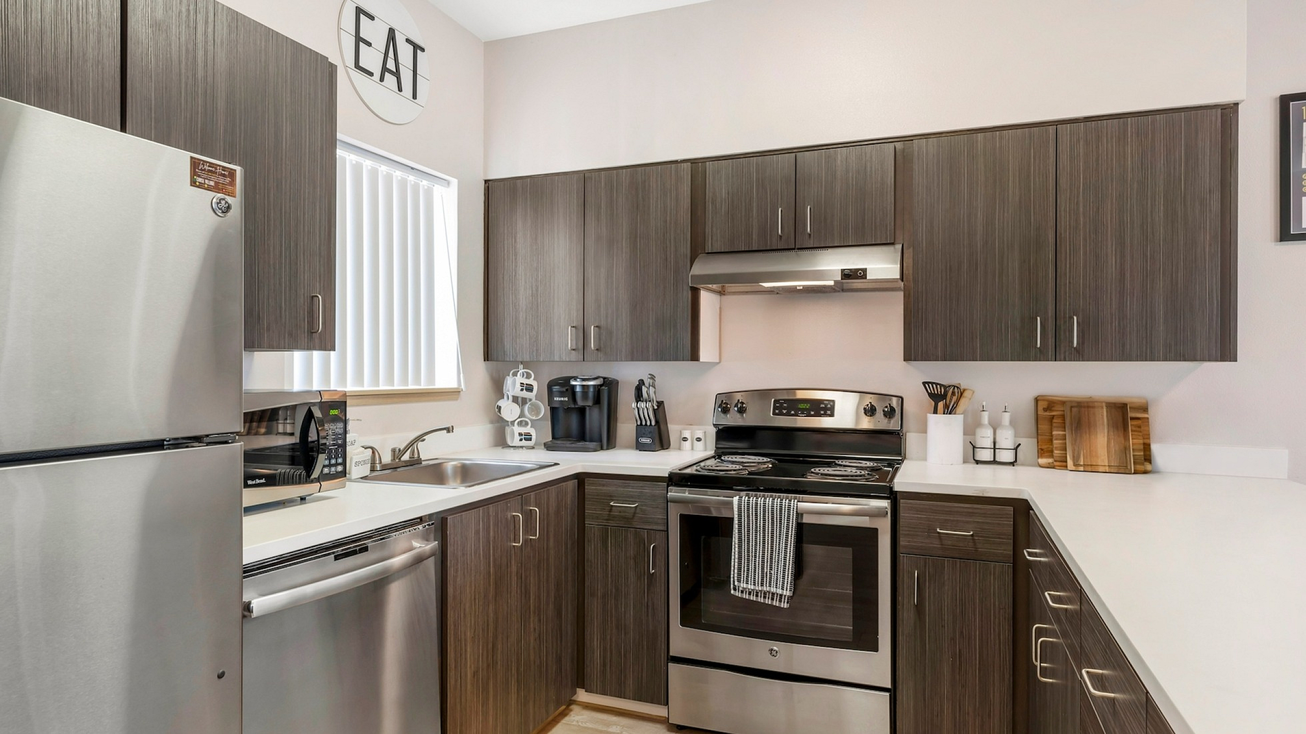 Modern kitchen with sleek stainless steel appliances, dark wooden cabinets, and a bright, inviting atmosphere.