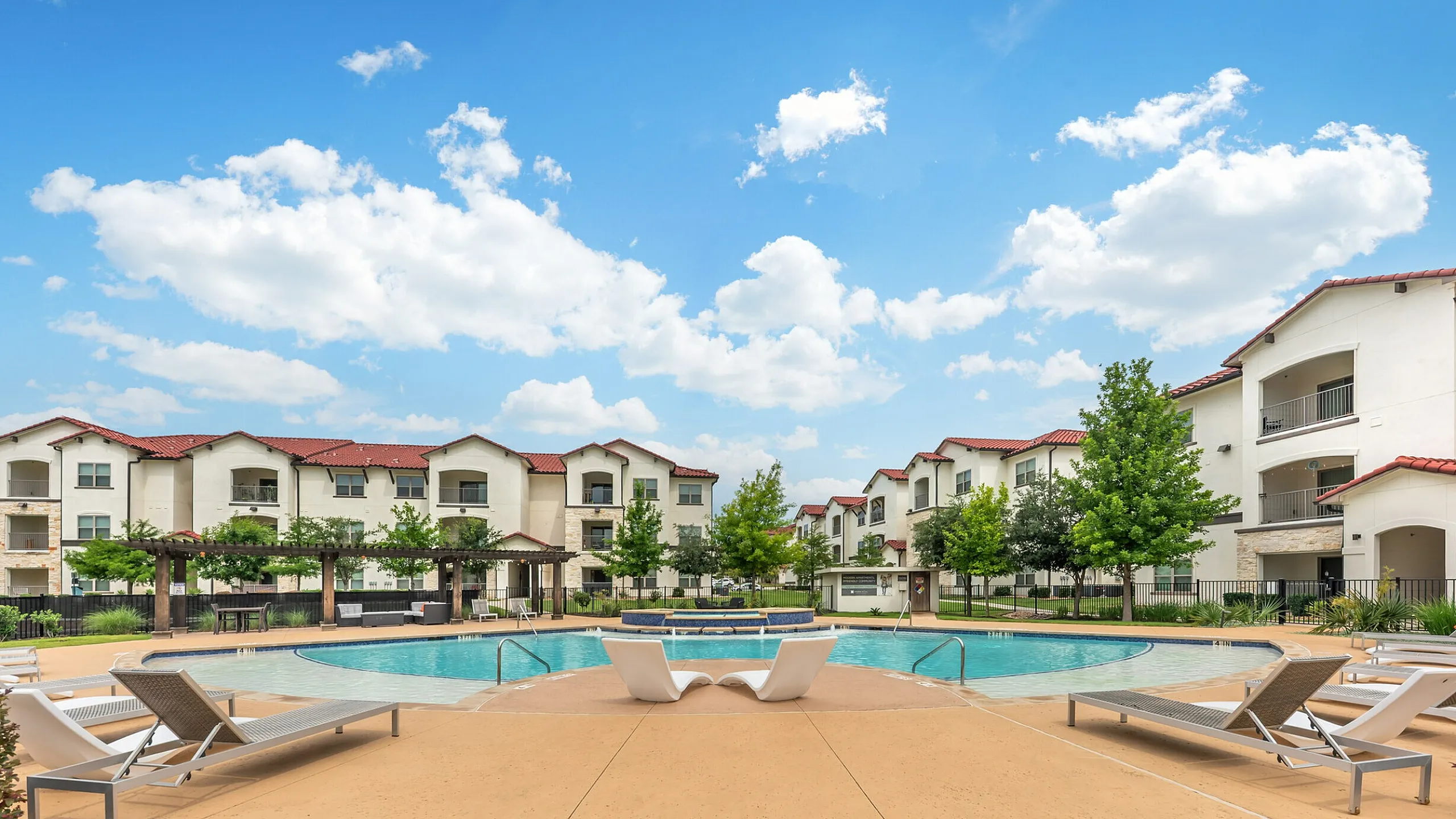 Resort-style poolside area with loungers and apartment buildings at Stone Hill in Pflugerville, TX