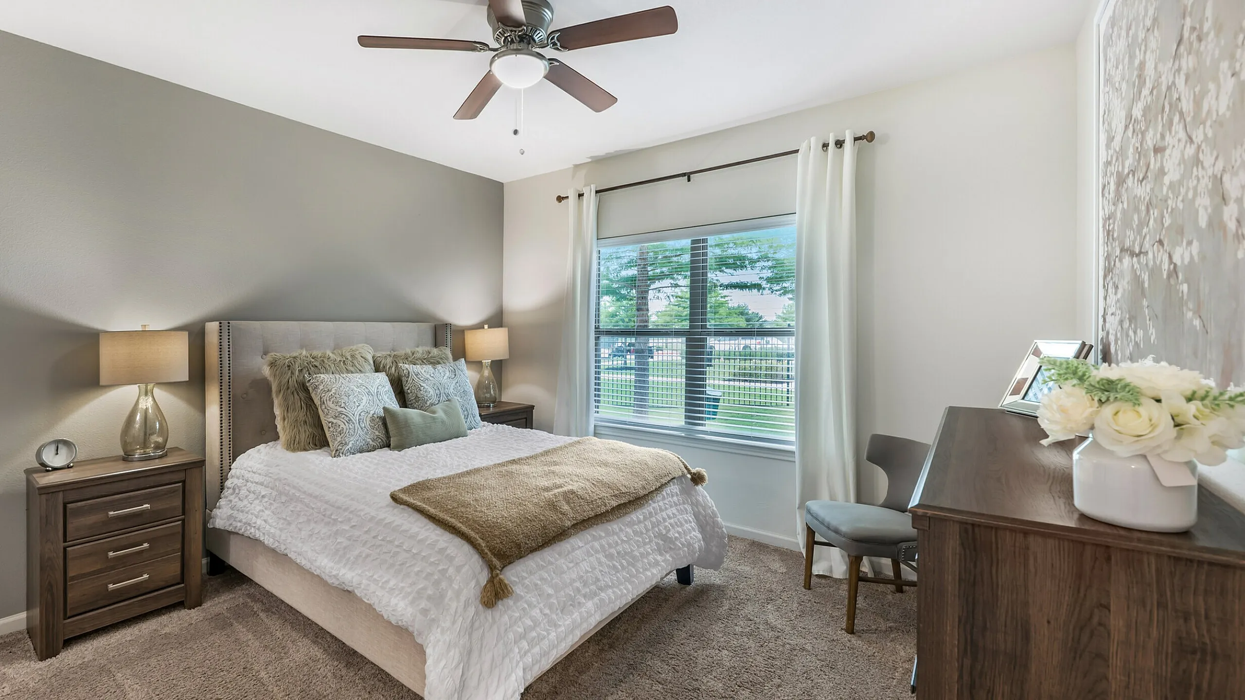 Elegant bedroom with plush carpet, decorative pillows, and large window views at Stone Hill Apartments in Pflugerville, TX