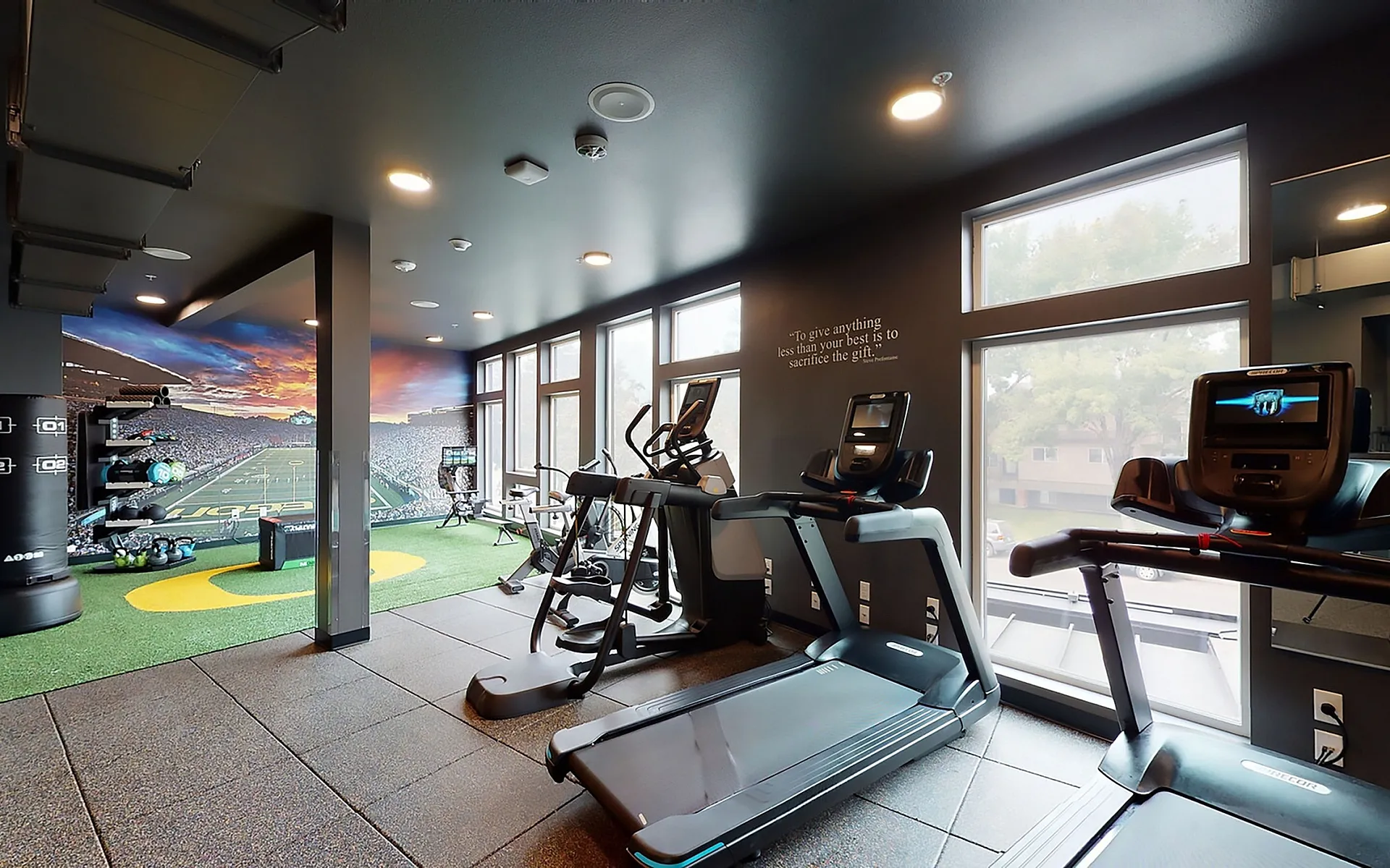 Fitness Center with Treadmills and Sports-Themed Wall Art at The Flats at Chase Student Apartments in Eugene, OR