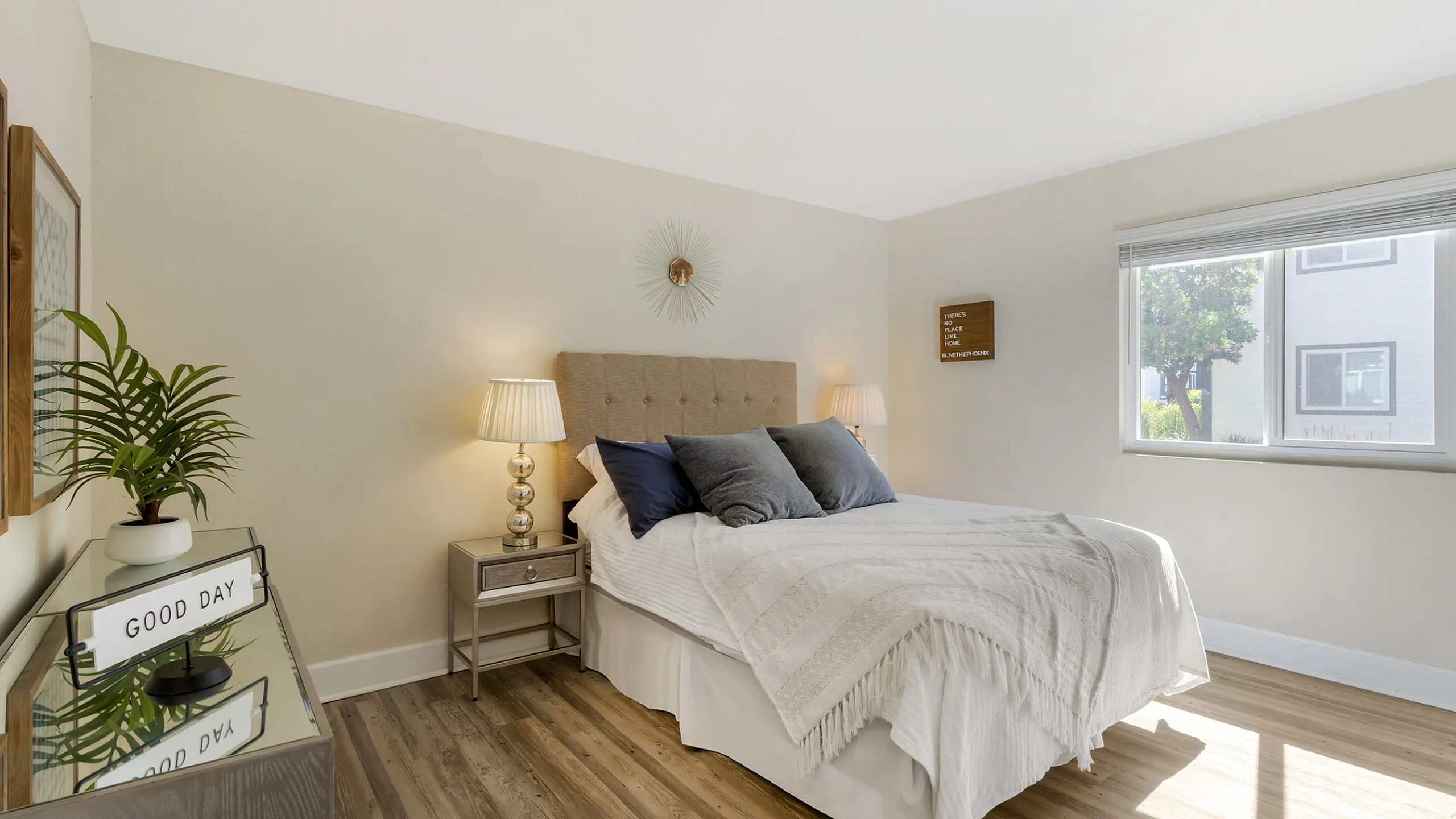 The Phoenix Sacramento bedroom with a cozy bed, elegant decor, soft lighting, and a sunlit window view.