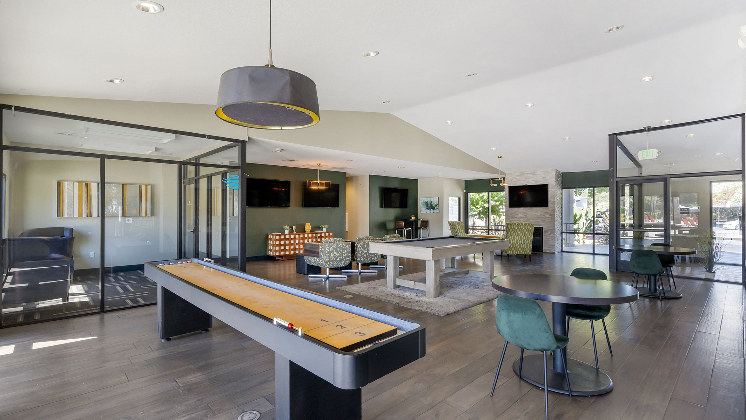 The Phoenix Sacramento communal lounge area featuring a sleek shuffleboard table, stylish seating, and large windows for natural light.