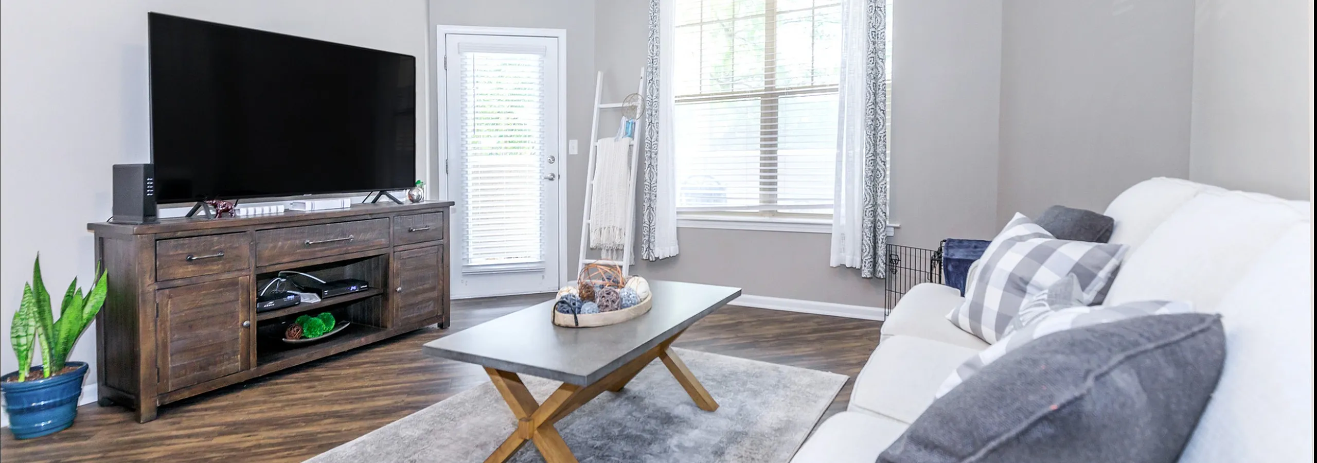 Bright and inviting Corbin Crossing living room with a large screen TV, modern decor, and a plush sofa, perfect for relaxation and entertainment.