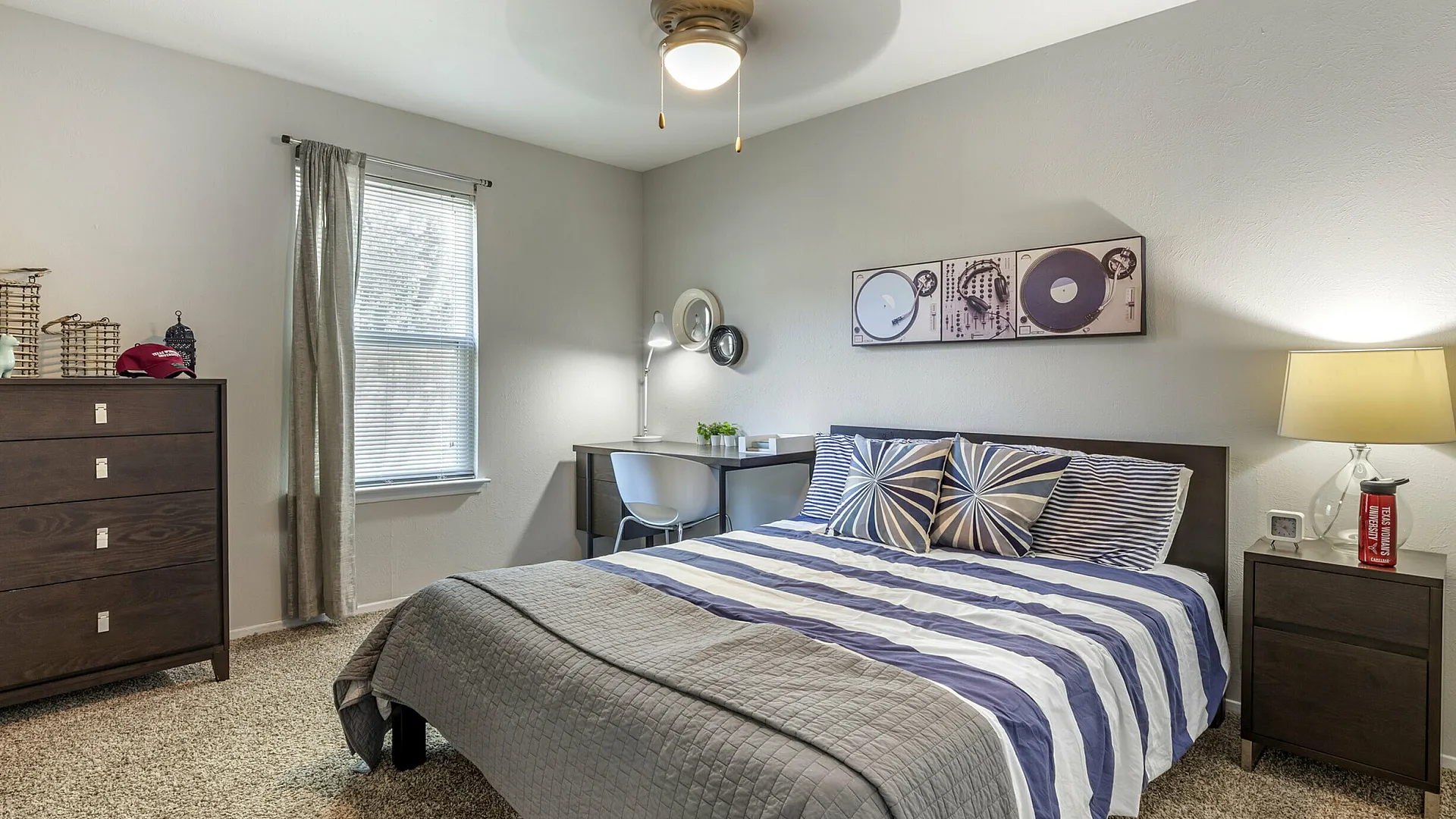 Stylish bedroom with striped bedding and modern desk in a student apartment at The Venue in Denton, TX near University of North Texas